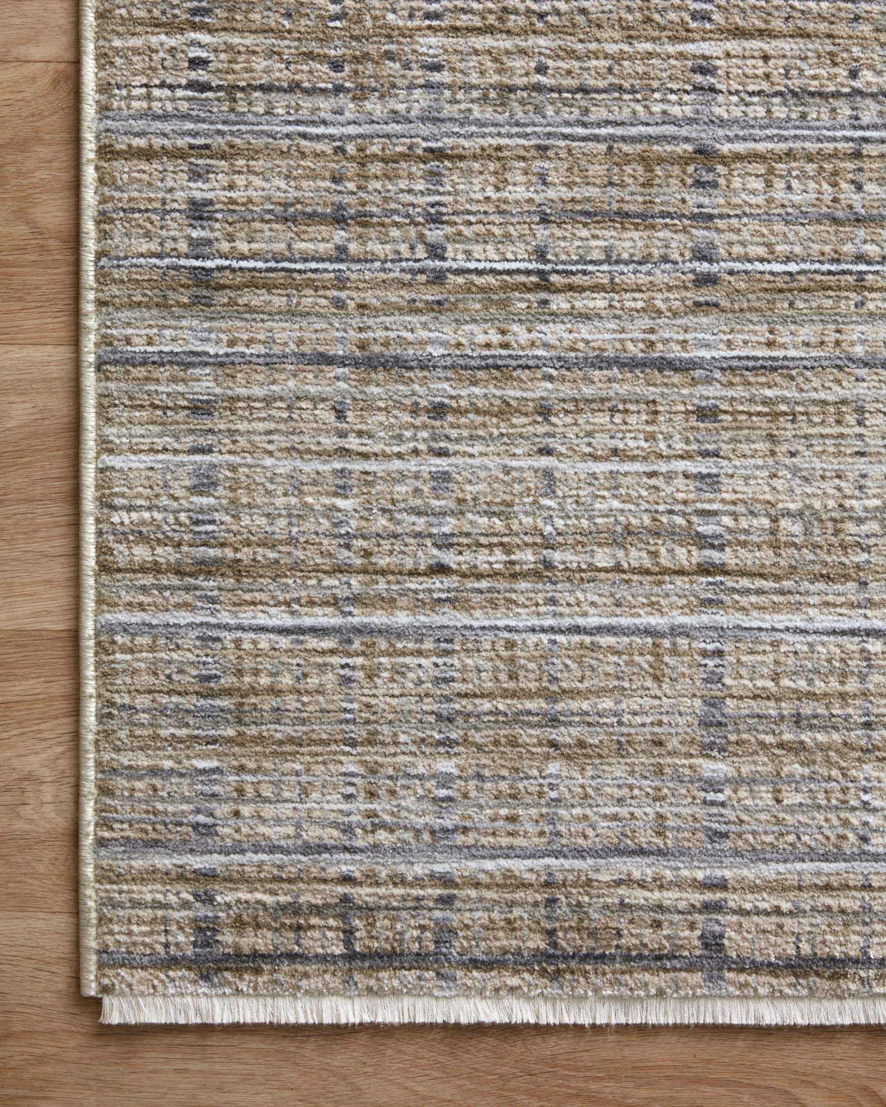 Rug corner on wood floor, featuring light beige surface with blue-gray stripe blocks