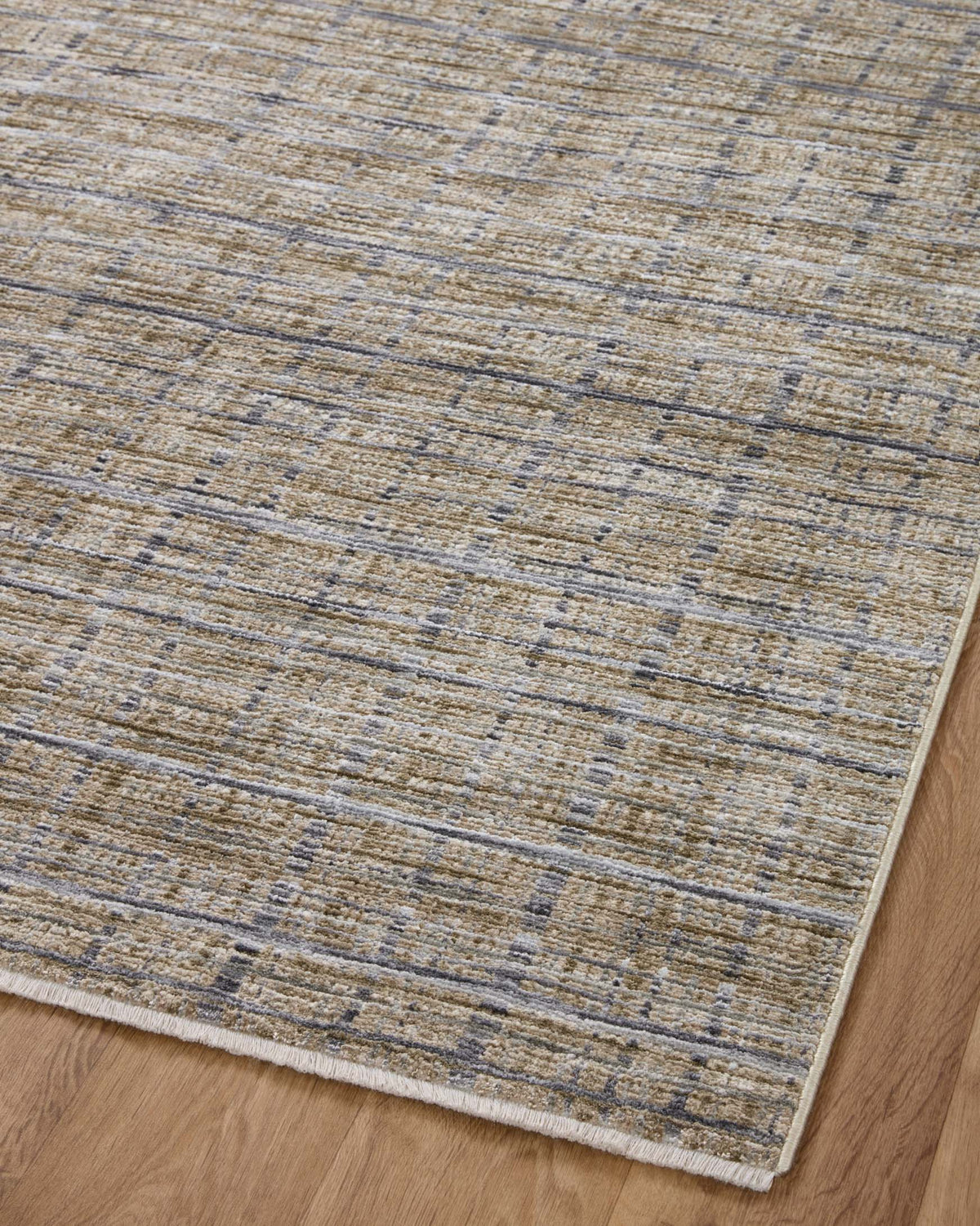 Corner view of beige accent rug with blue-gray and charcoal linear pattern, flatwoven texture.