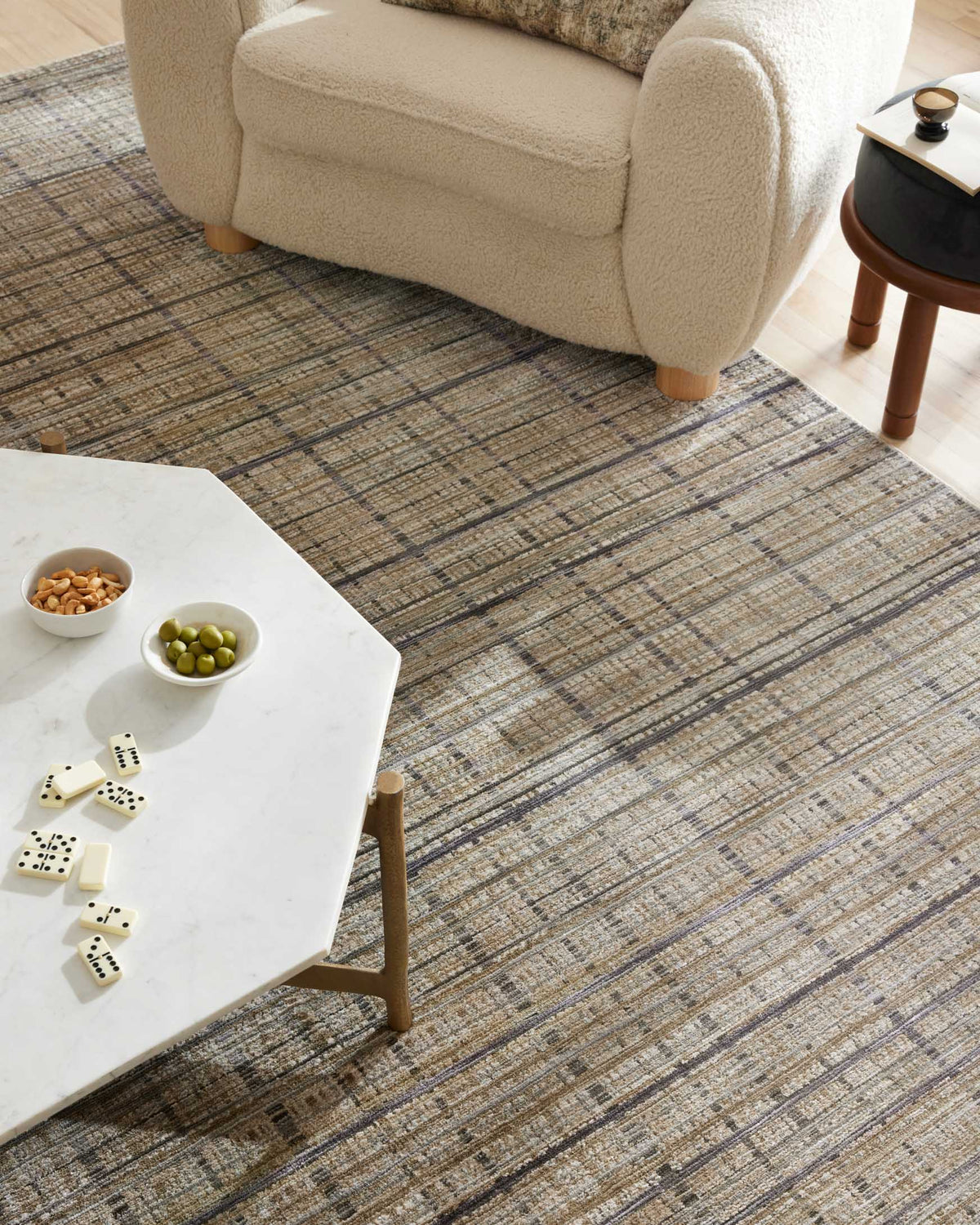 Corner view of accent rug showing beige and charcoal grid stripes across surface