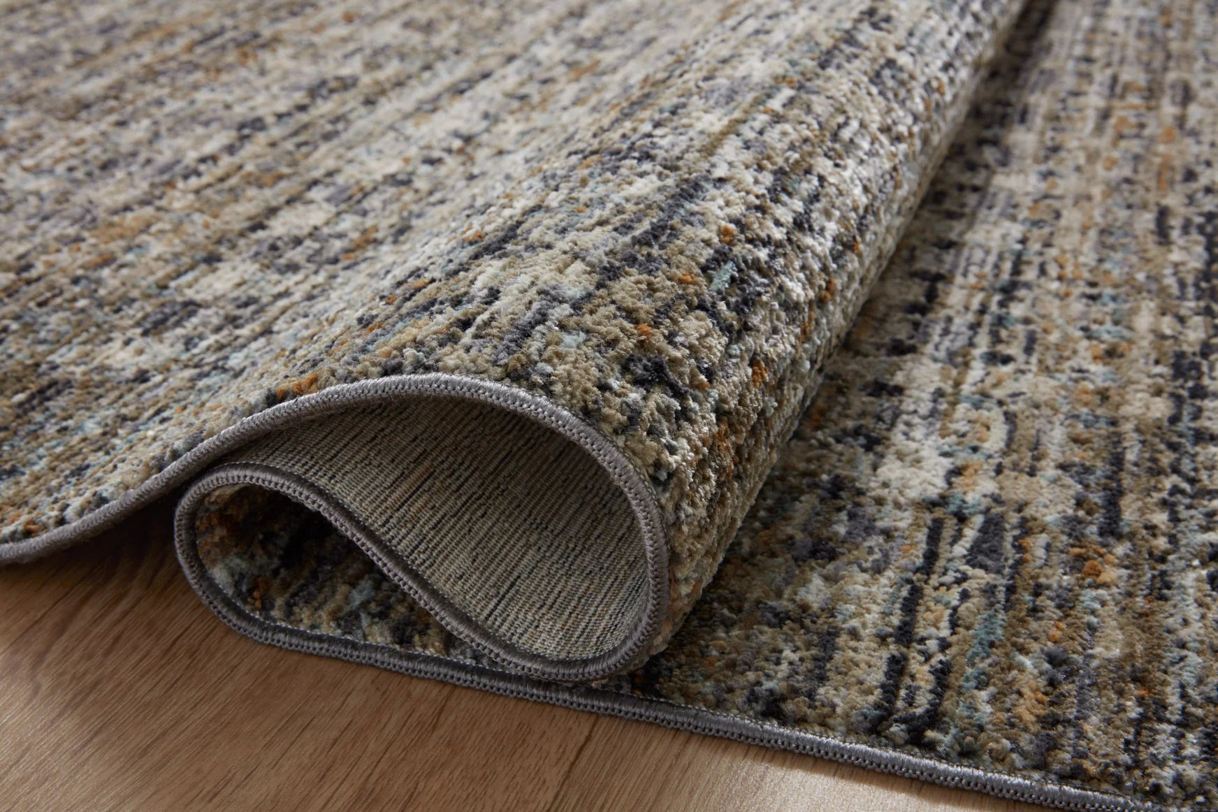 Close-up of charcoal gray area rug edge with stitched border and flat woven pile