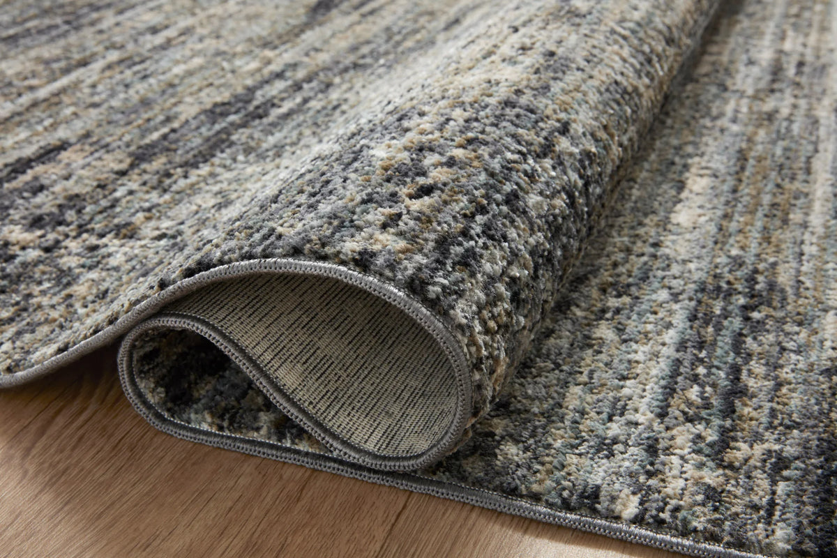 Close-up of slate gray accent rug edge with stitched border and short pile