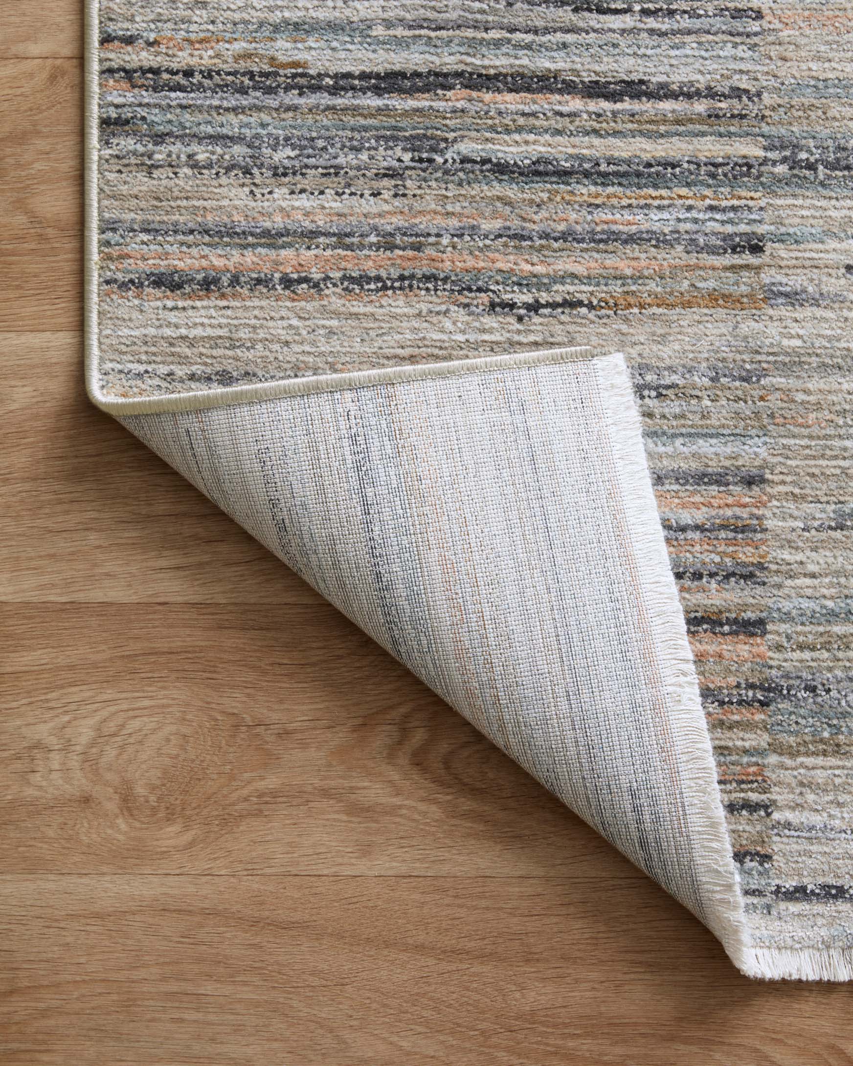 Corner view of runner rug layered backing with gray-blue and tan striped pattern.