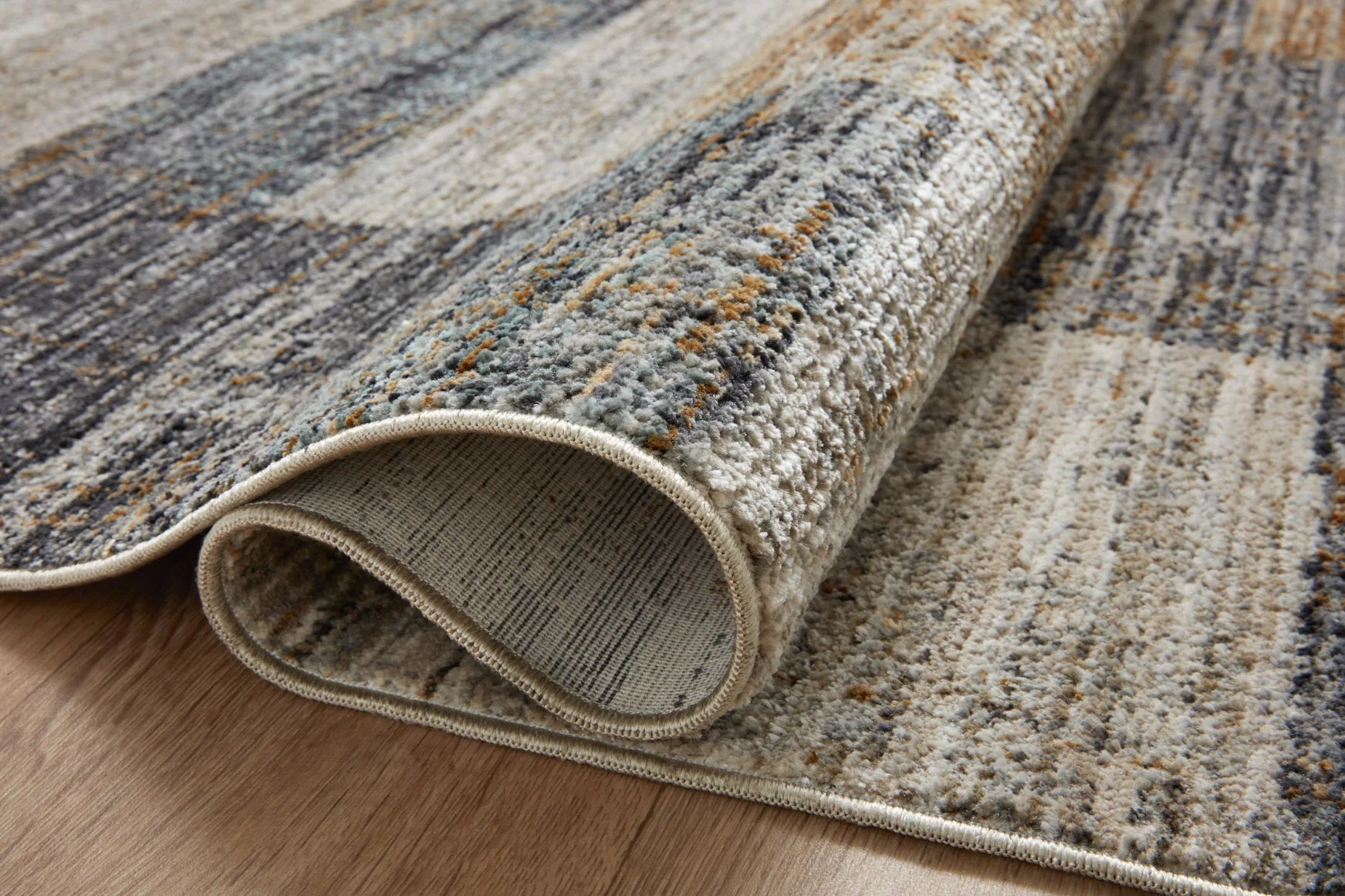Grey and gold runner rug rolled edge showing low pile texture and stitched binding