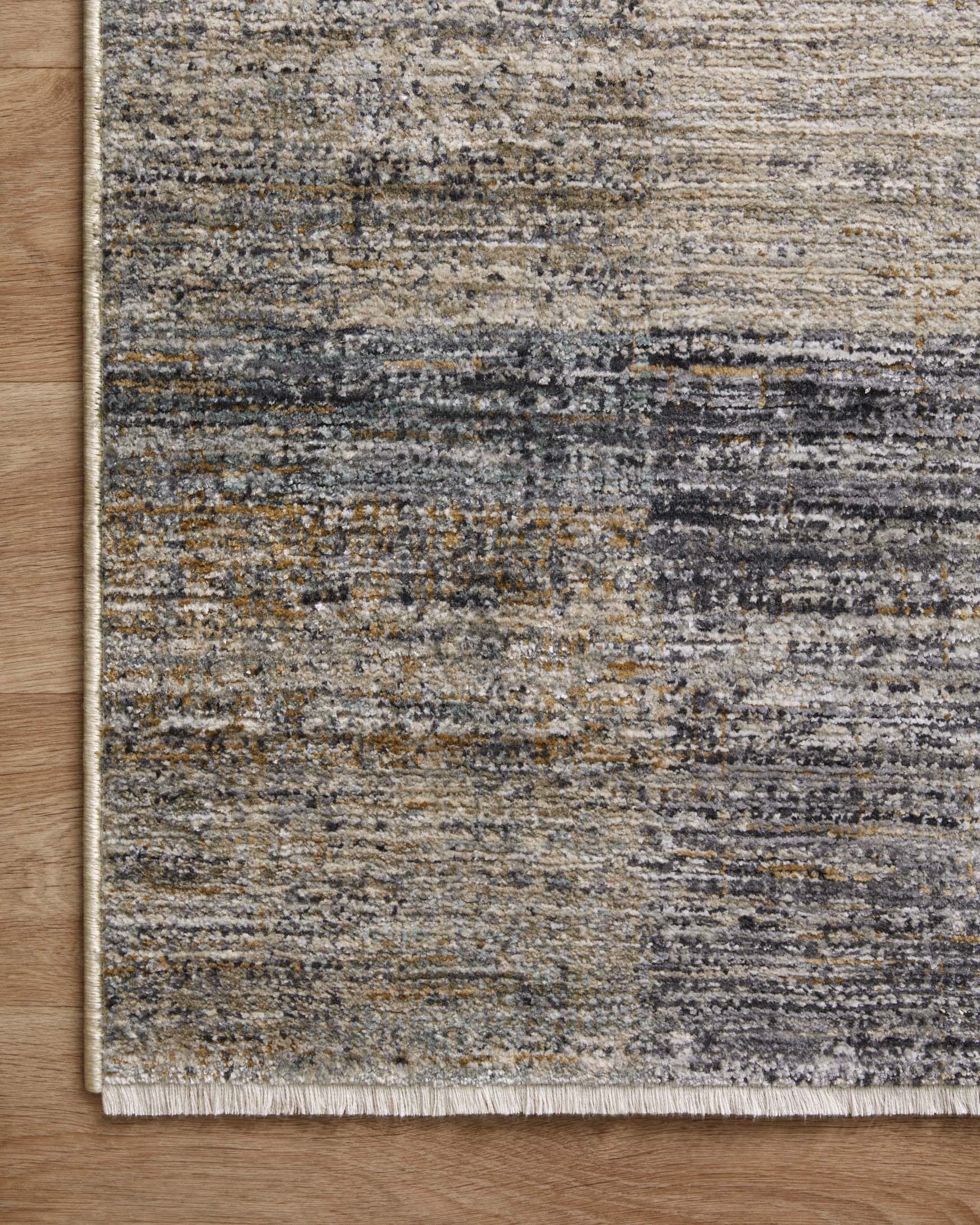 Grey and gold accent rug with visible border edge on light wood flooring