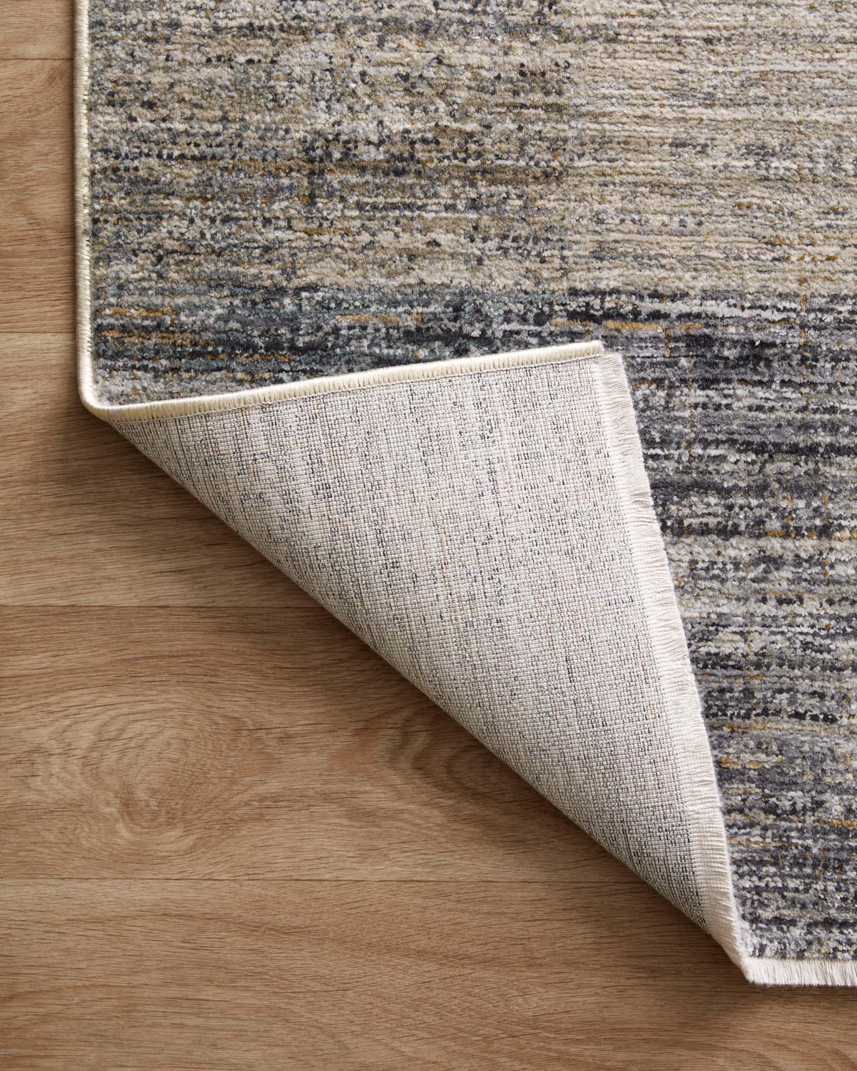 Grey and gold abstract rug corner with backing exposed, underside close-up