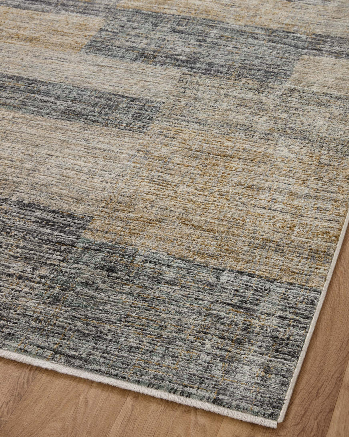 Grey and gold abstract runner rug angled view with border on hardwood floor.