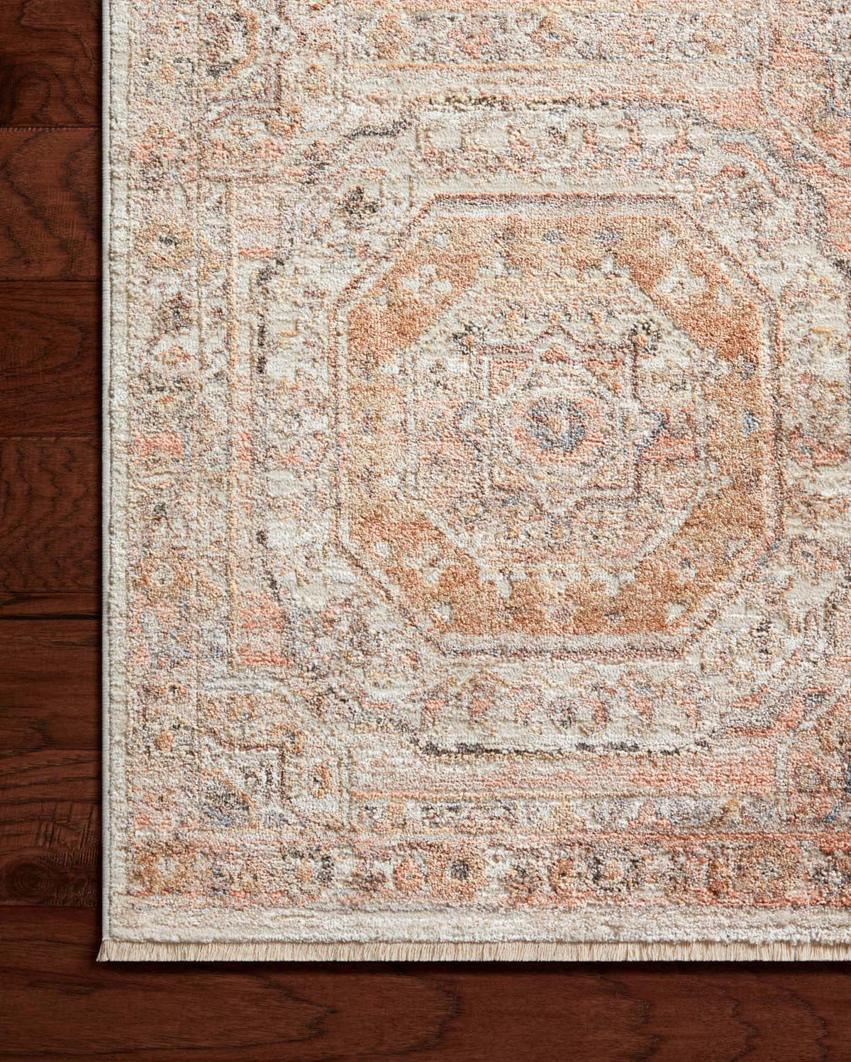 Apricot distressed rug with ornate medallion design and short fringe along edge