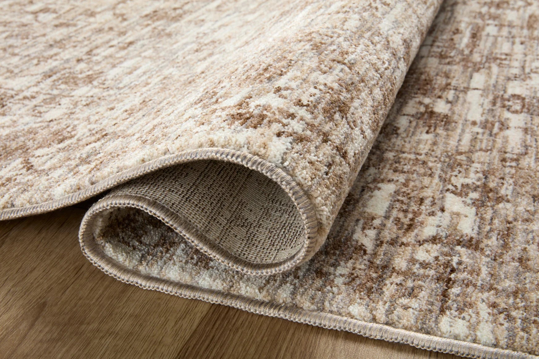 Runner rug roll-up view showing woven texture and fringed edge in tan and brown