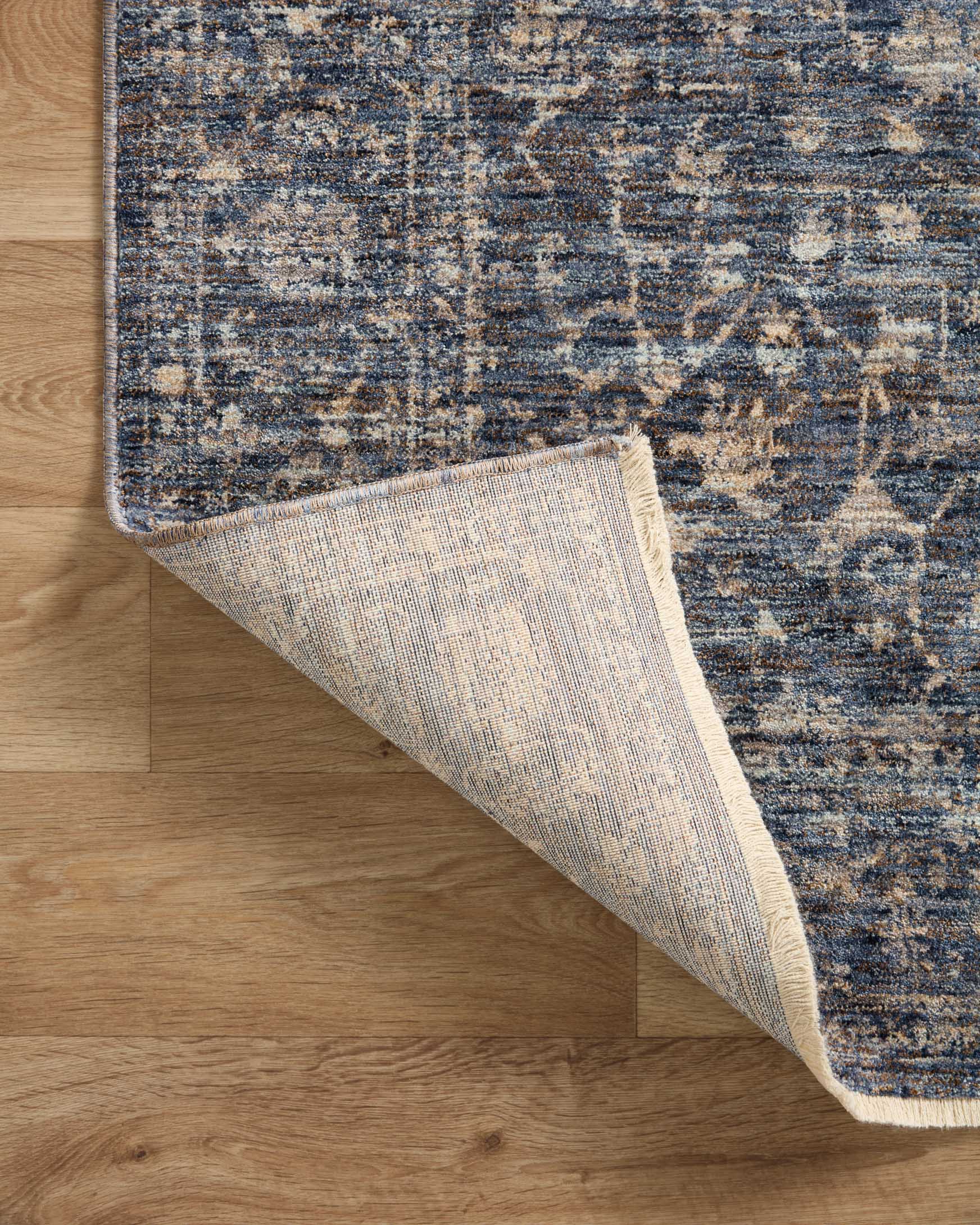 Traditional area rug with blue top and light beige reverse visible at folded edge
