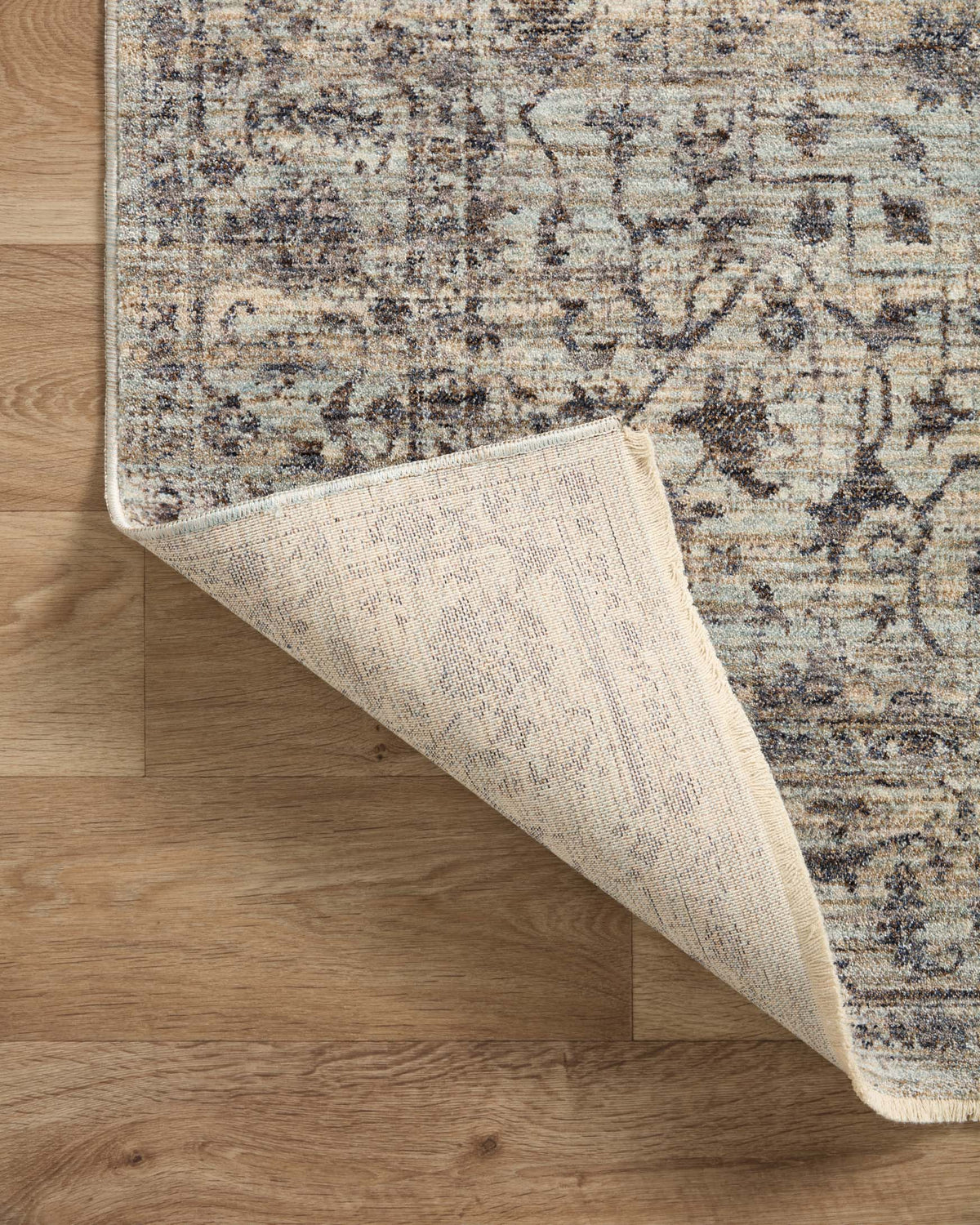 Traditional area rug corner in mist and charcoal, showing underside pile texture.