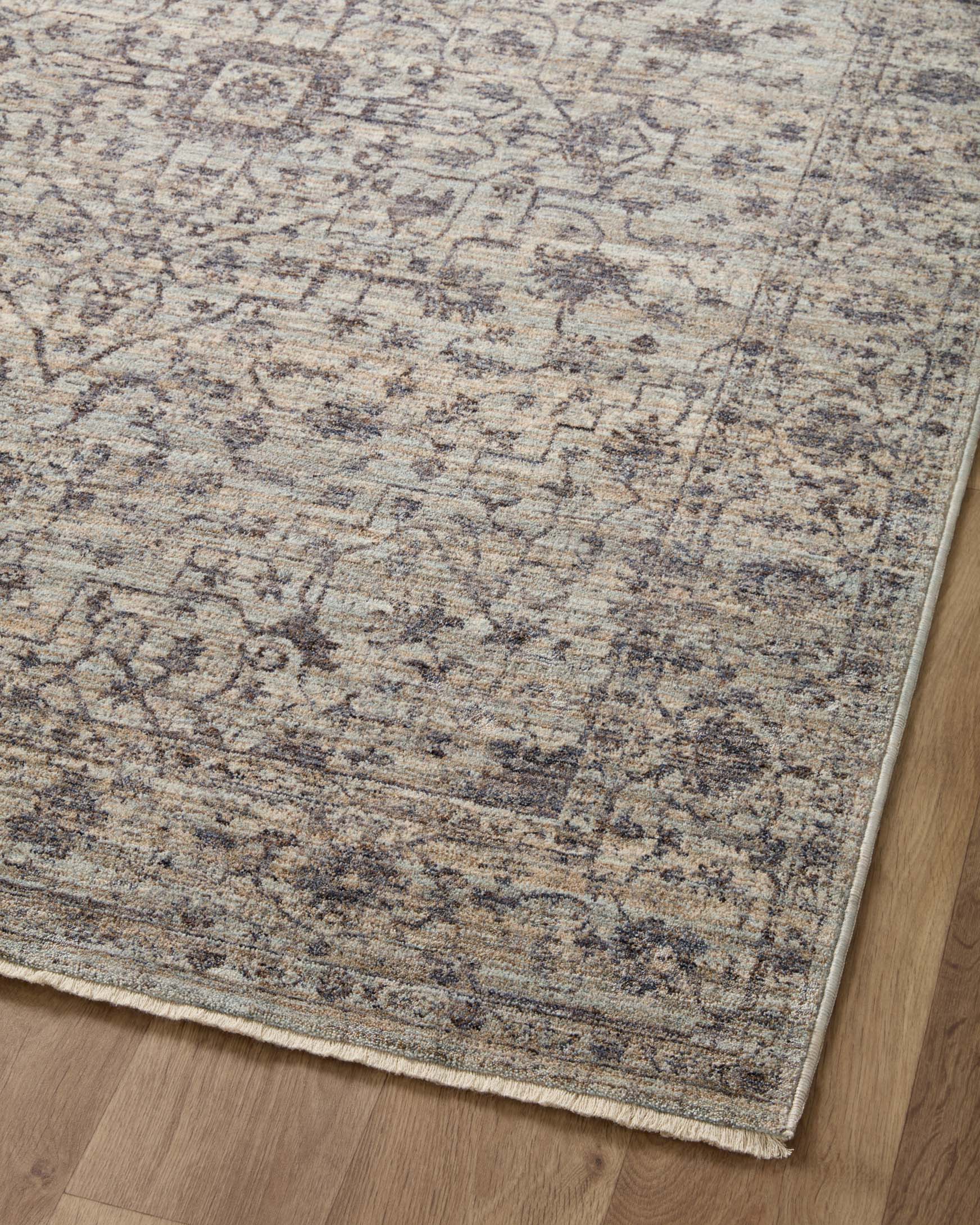 Mist and charcoal traditional area rug with distressed geometric pattern and border trim.