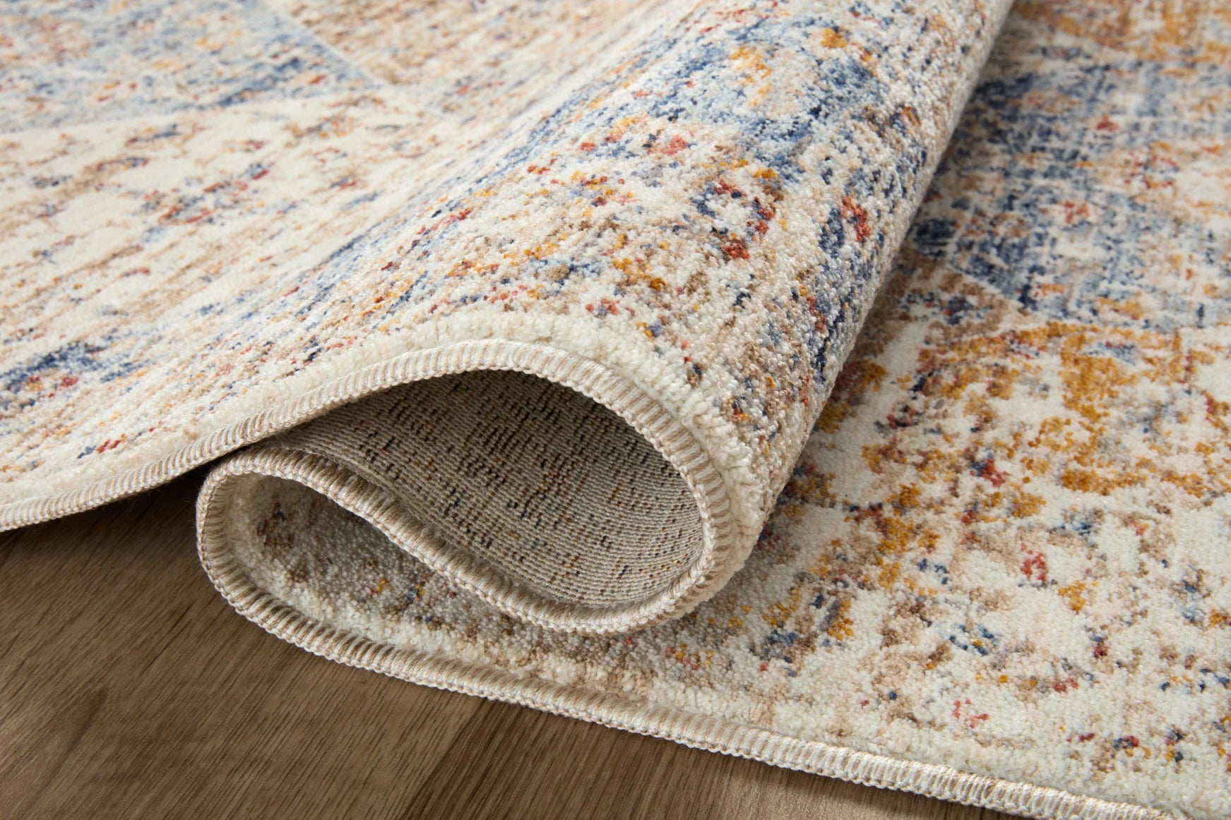 Traditional area rug with ivory and blue distressed pattern; braided fringe border