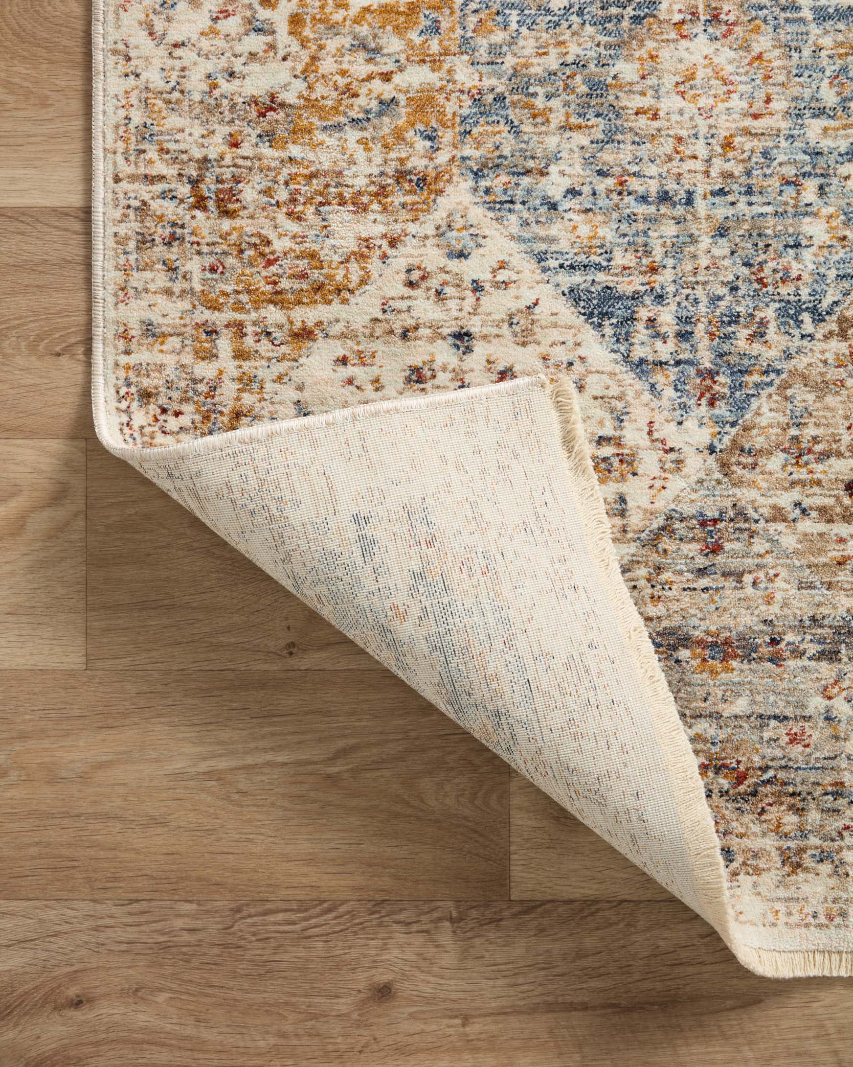 Traditional area rug folded corner showing ivory underside and blue-and-ivory top pattern
