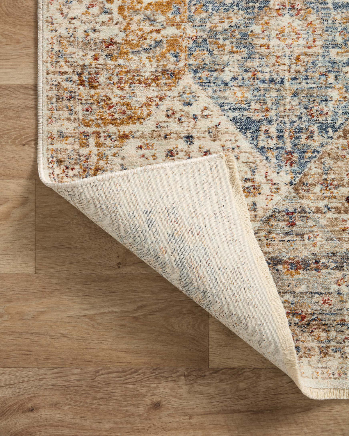 Ivory and light-blue area rug underside with distressed pattern and short fringe.