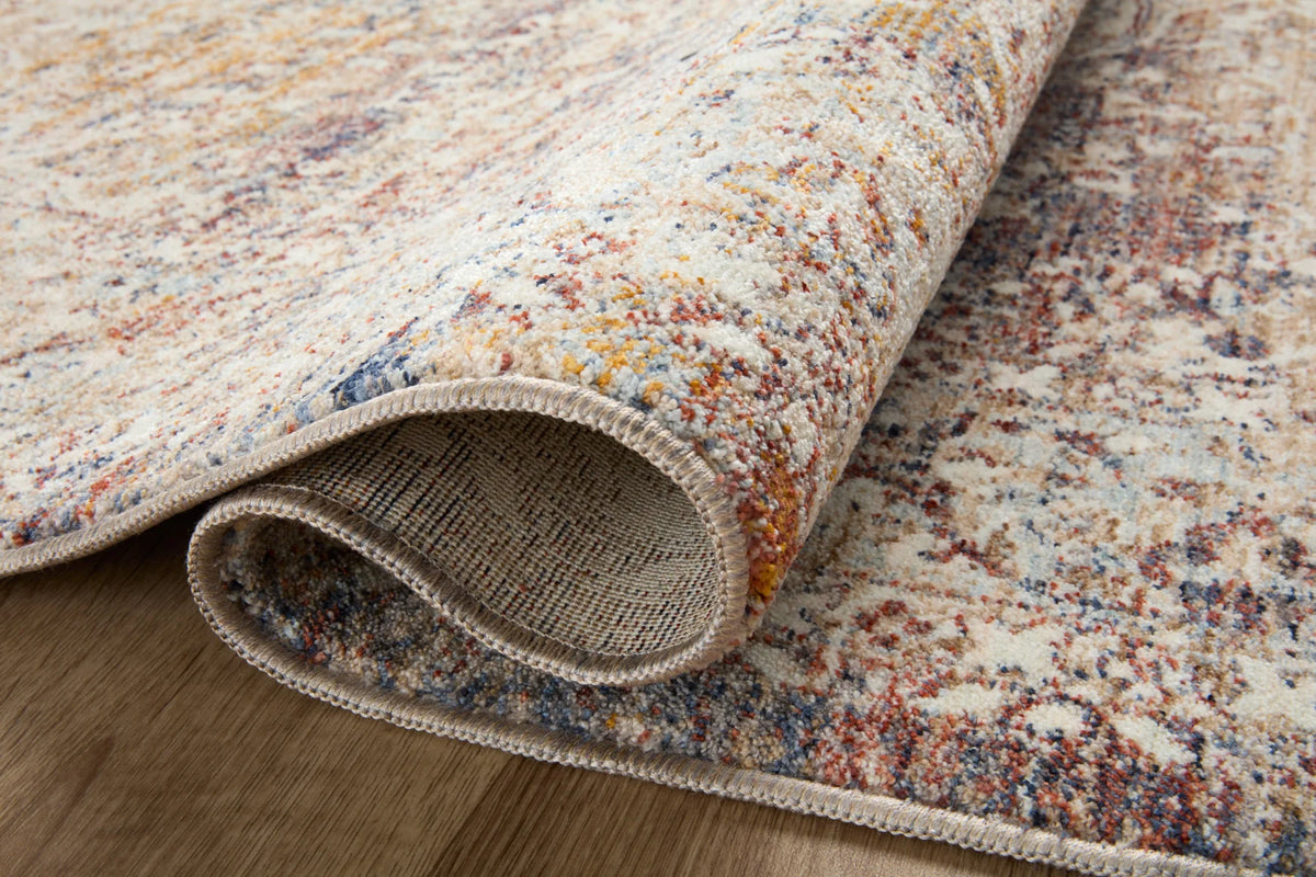 Rolled edge view of natural beige area rug with multicolor distressed pattern