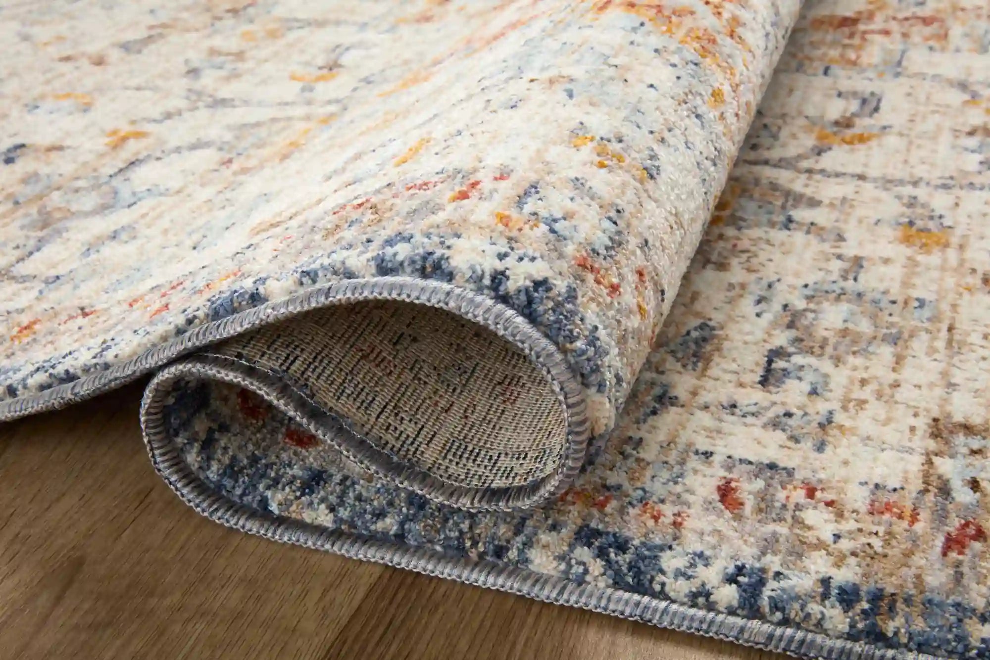 Accent rug rolled edge with gray binding; ivory pile with blue and orange/red distressed pattern.