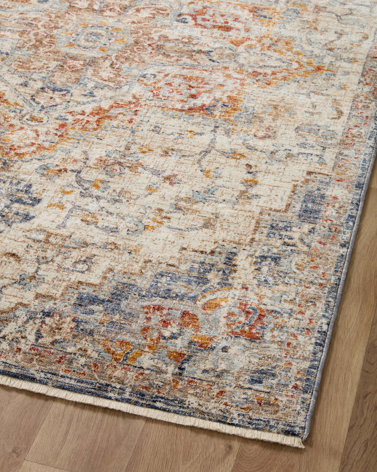 Traditional area rug featuring distressed pattern in cream ivory with blue and orange accents