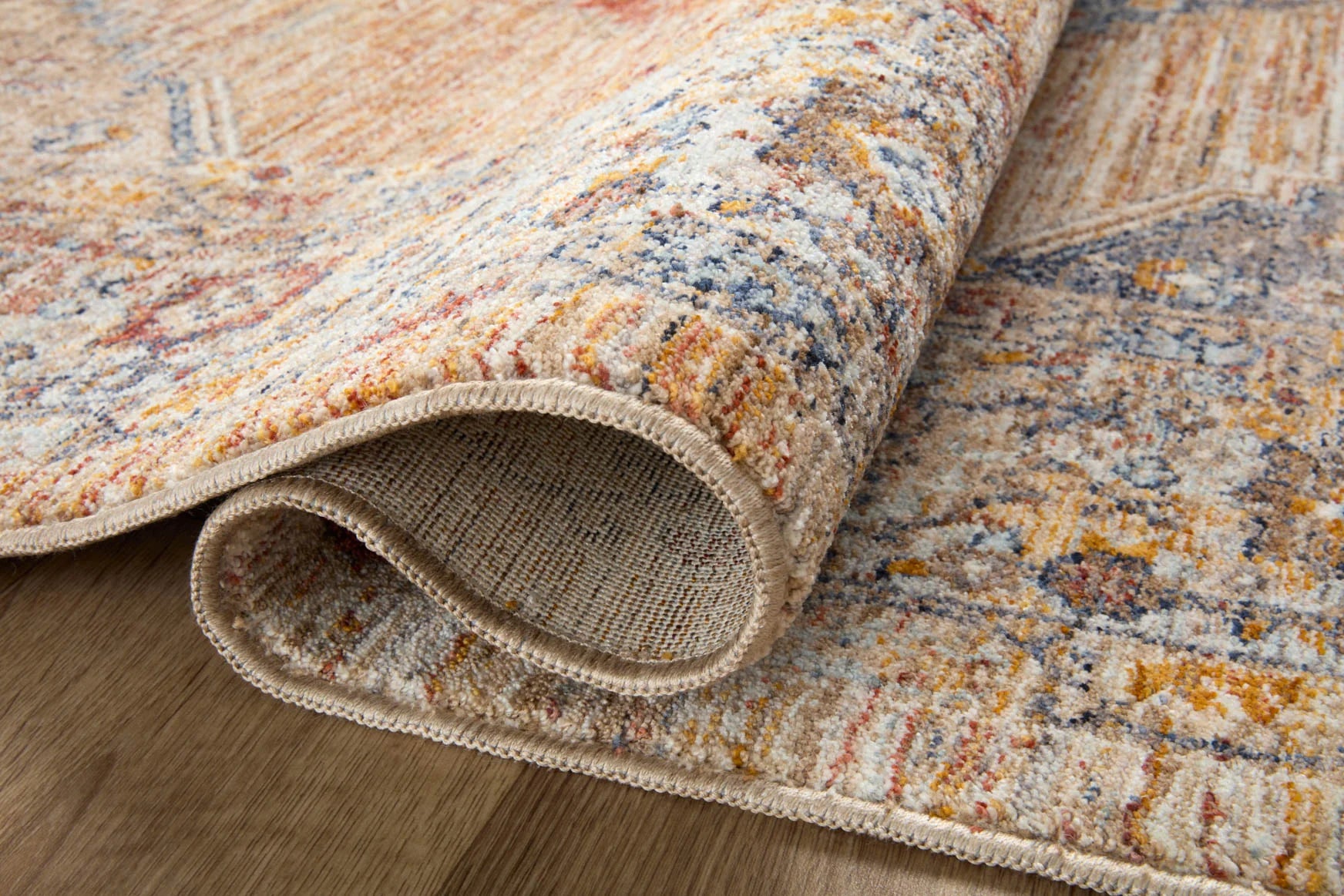 Accent rug corner detail with short fringe trim; blue, rust, and cream woven texture