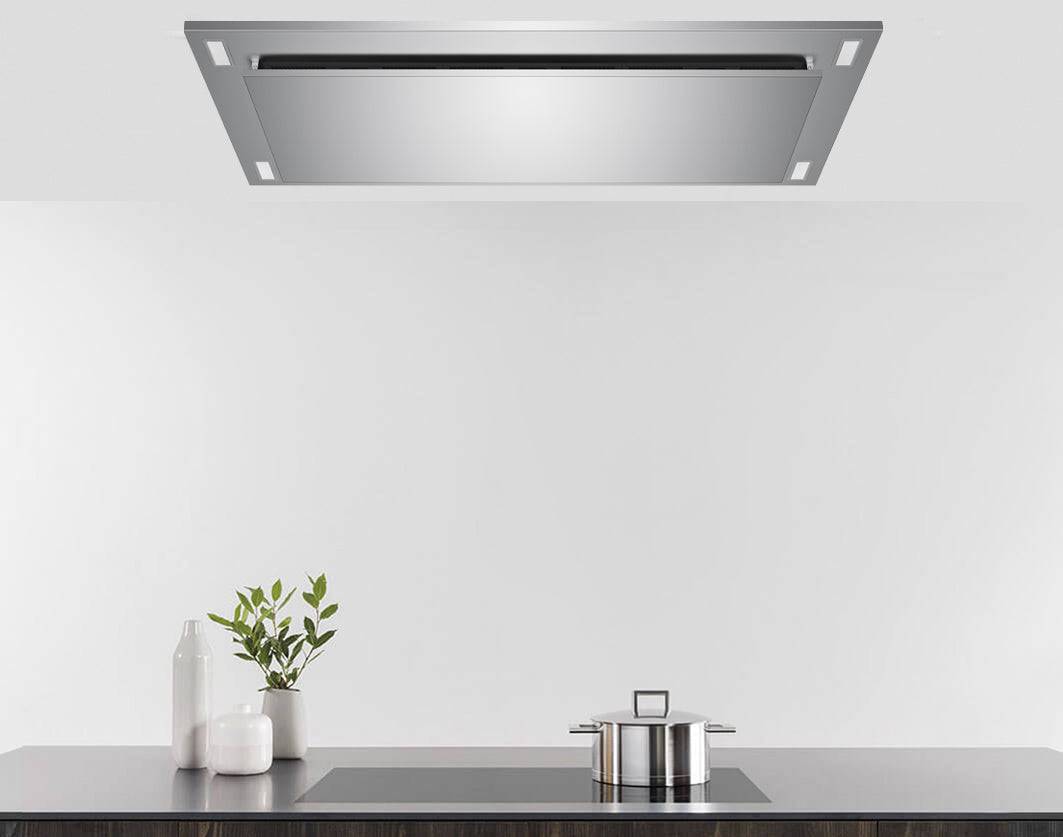 Stainless steel flush ceiling mount range hood above a kitchen cooktop