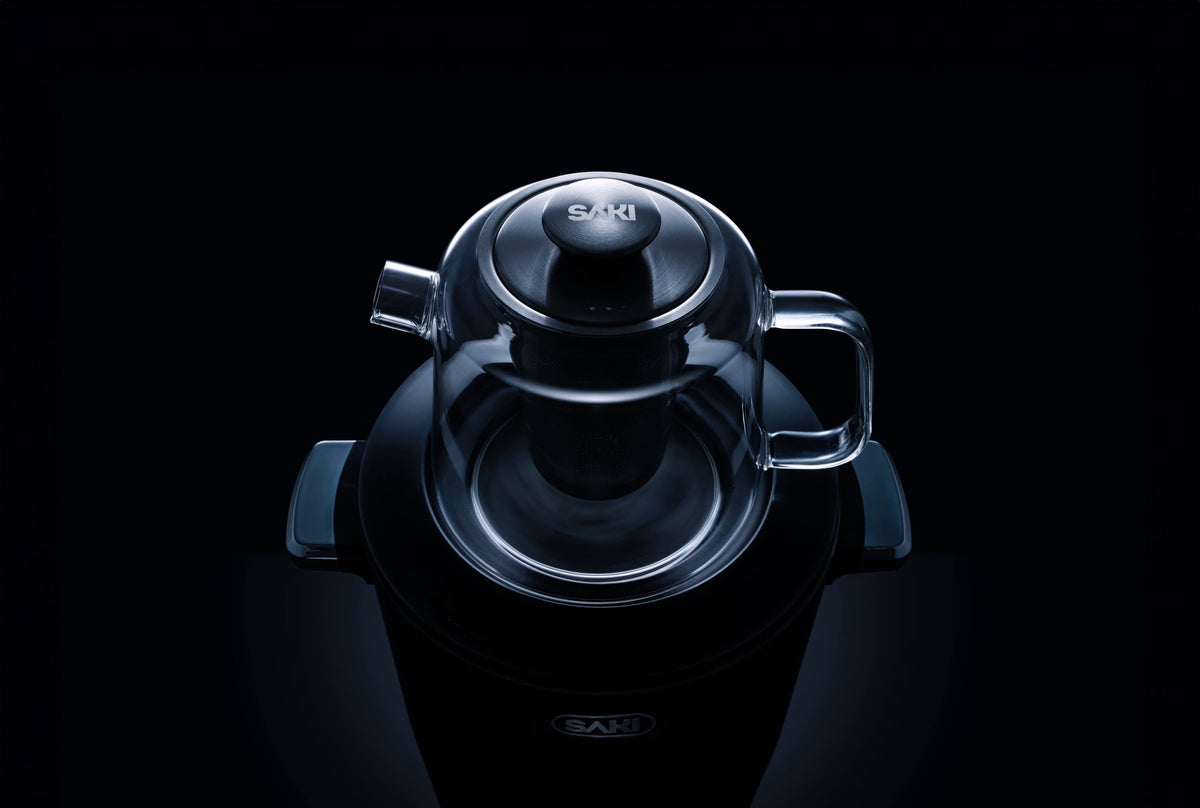 Black electric tea maker with rounded lid and side handles, top view.