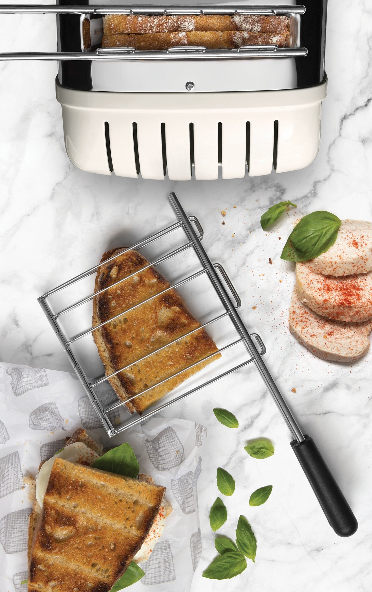 Chrome toaster base with open cage rack and bread slices on stone countertop