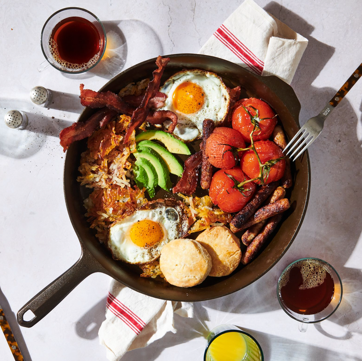 Cast iron skillet filled with cooked breakfast food, bacon, eggs, and vegetables