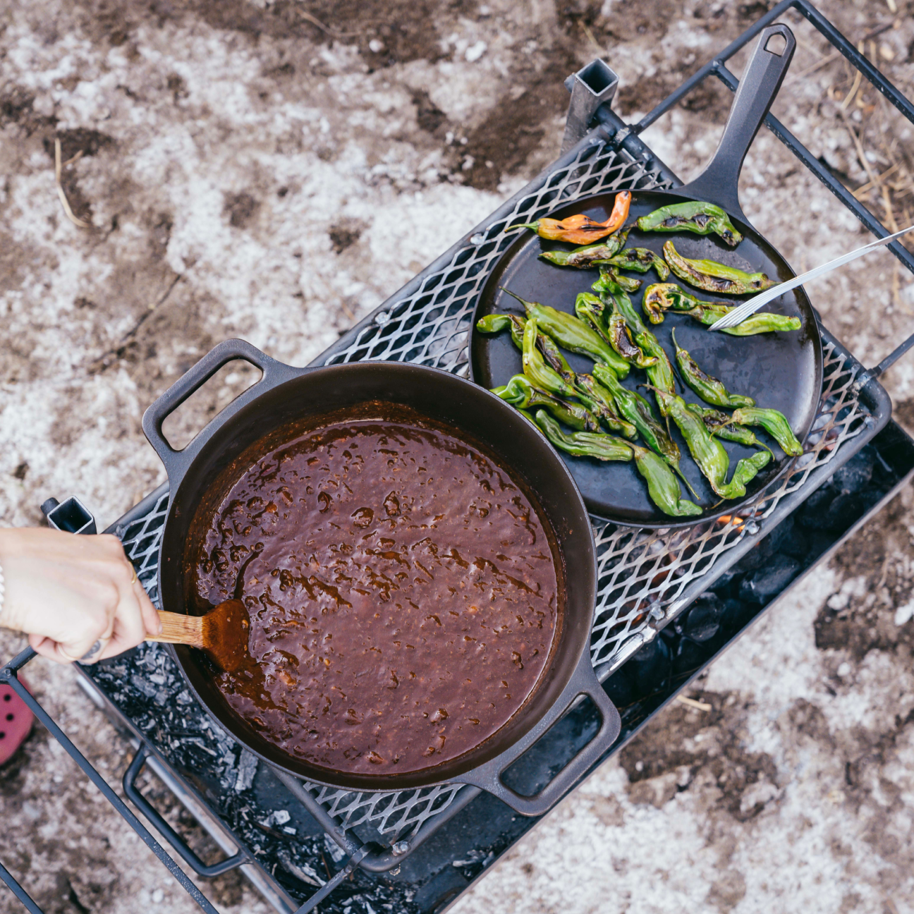 Black cast iron Dutch oven on a grill grate with dark liquid inside
