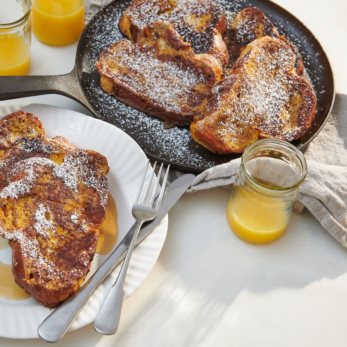 Round cast iron griddle with cooked toast pieces dusted with sugar