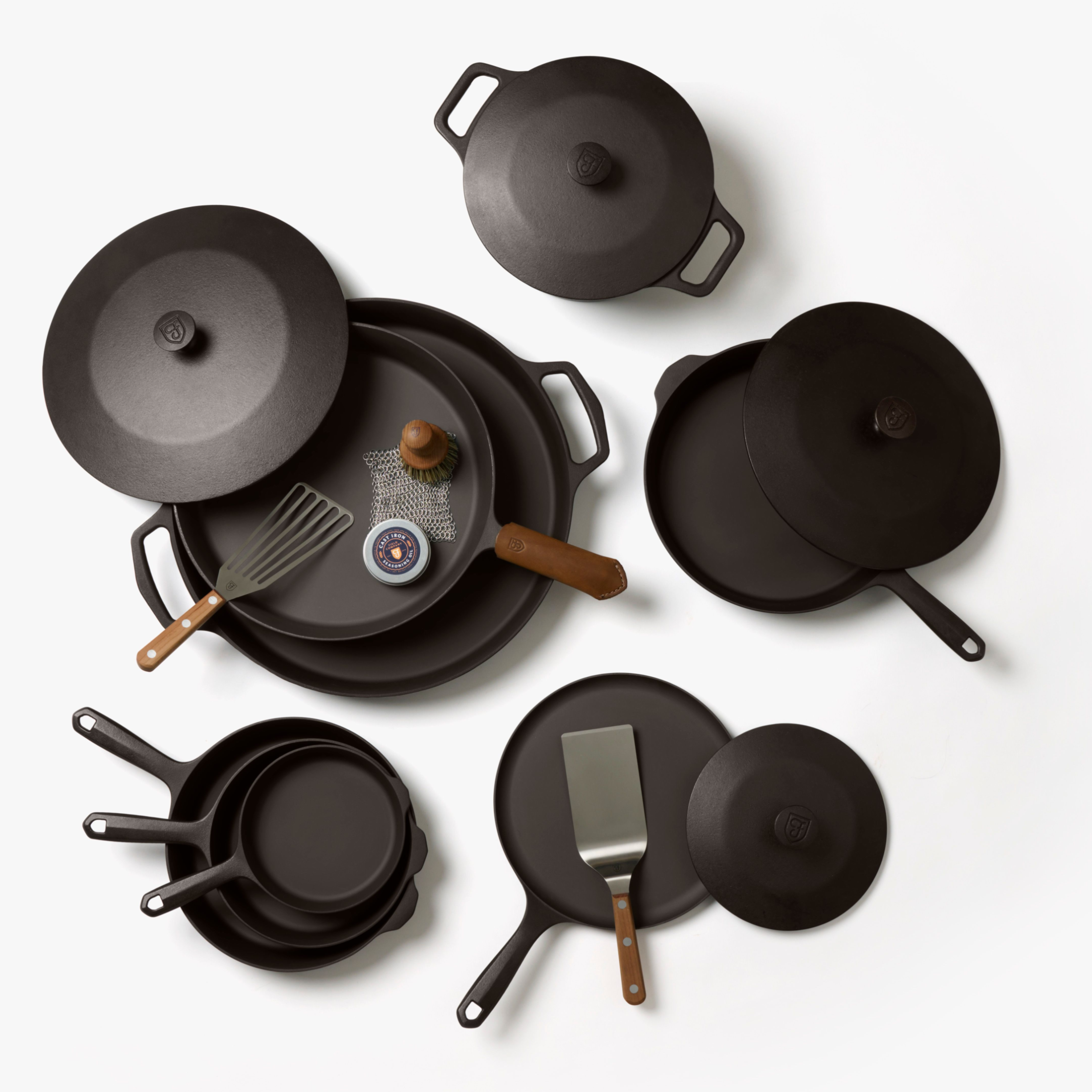 Cast iron cookware set with black pans and wooden-handled accessories
