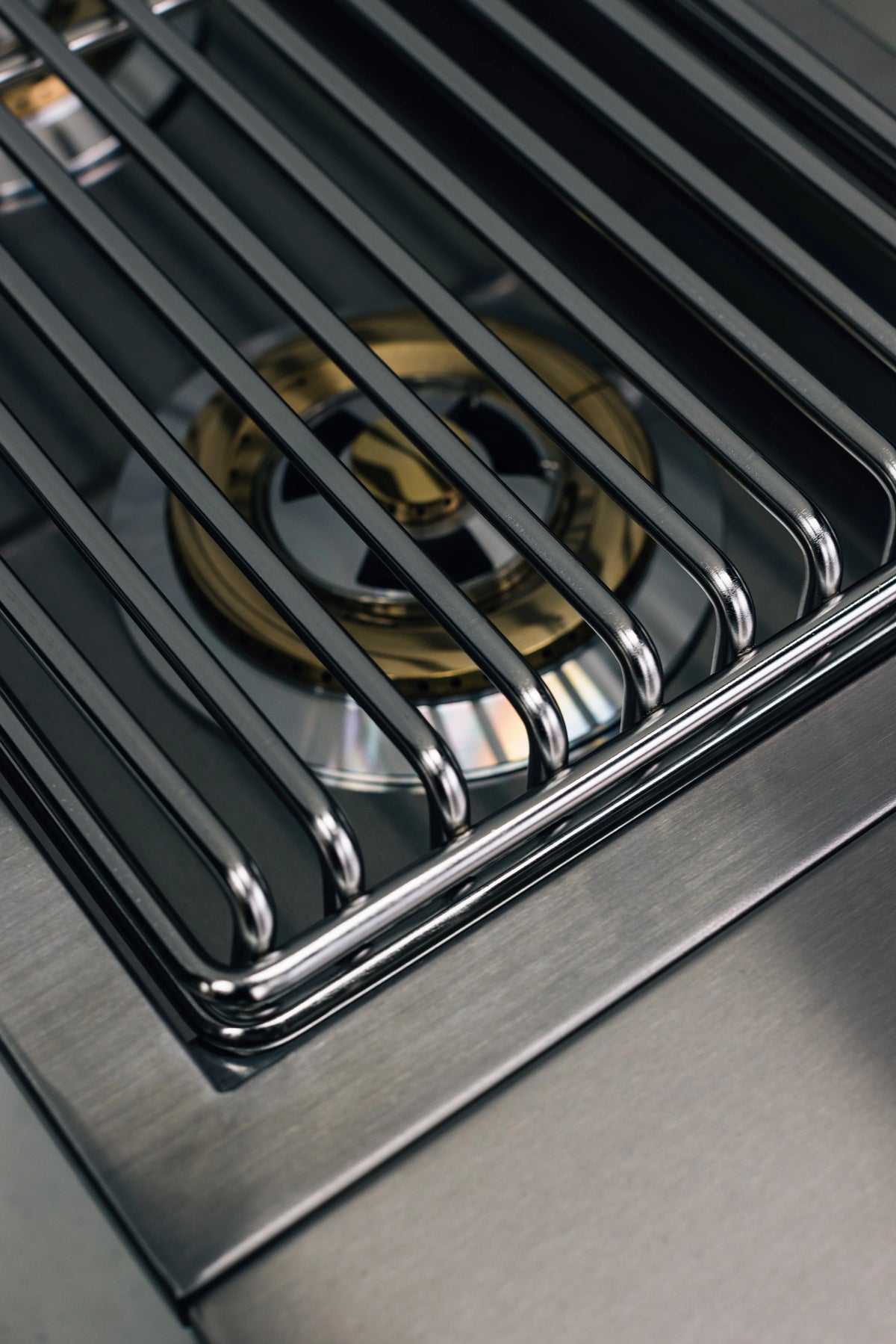 Stainless steel side burner grate with metal rods and partially visible burners