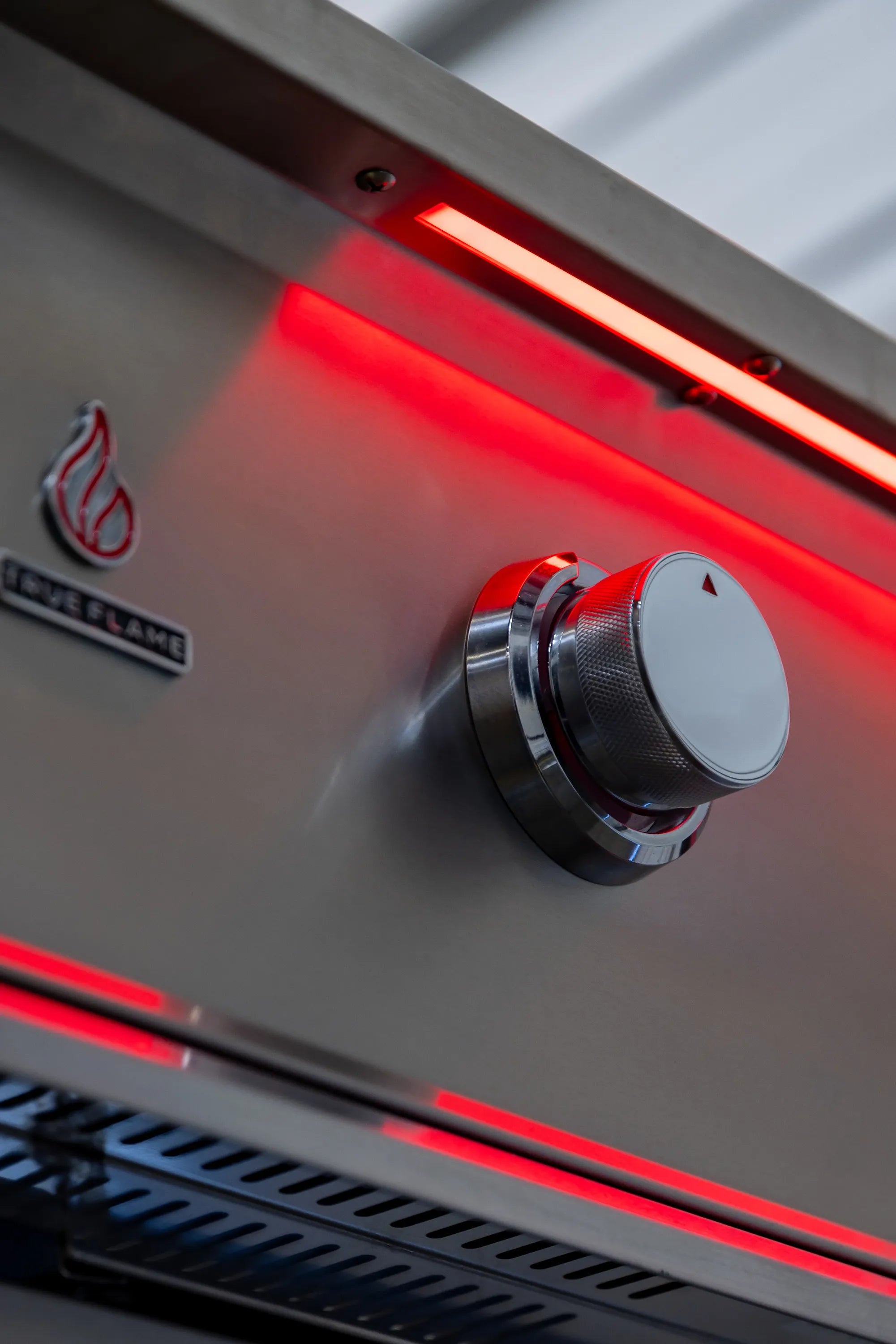 Infrared burner inside stainless grill, glowing red under hood, with control knob.