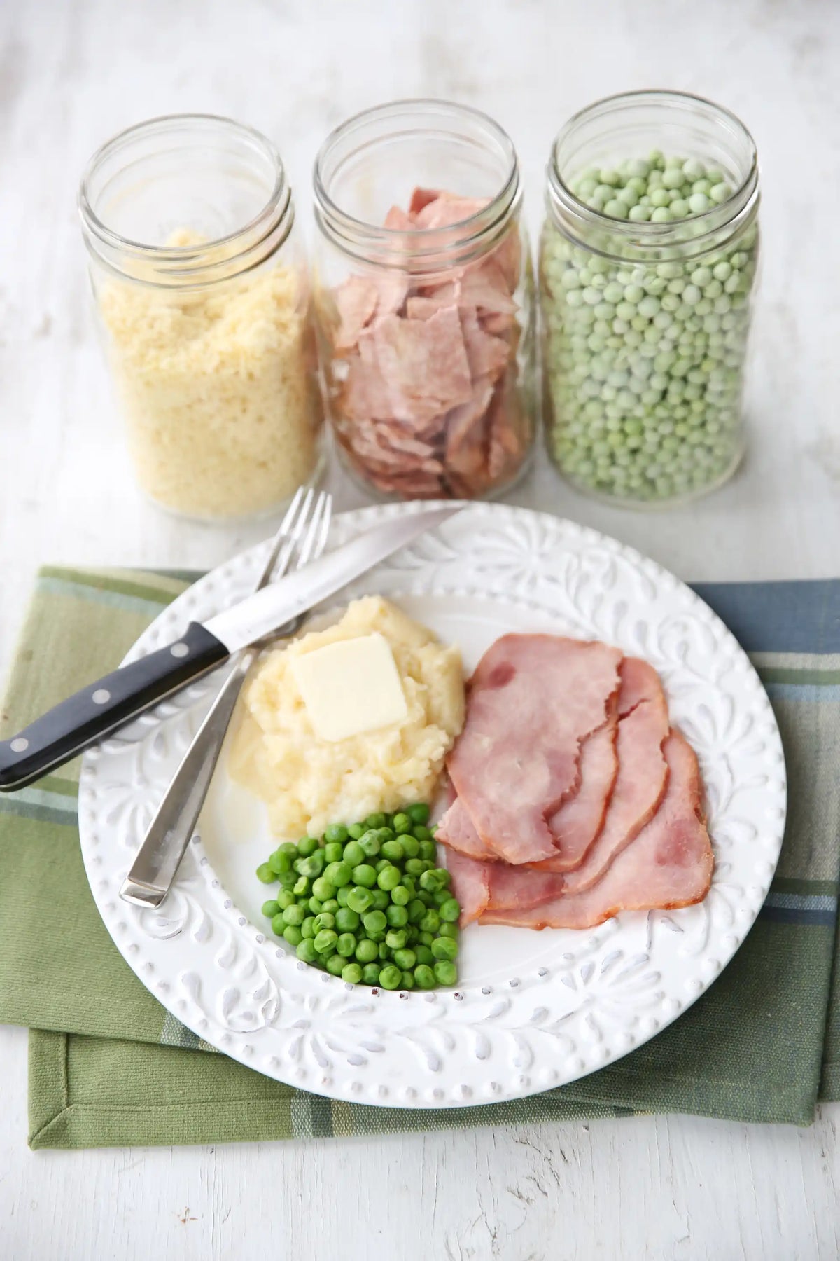 Freeze-dried foods on plates with peas, sliced meat, butter, and three ingredient jars