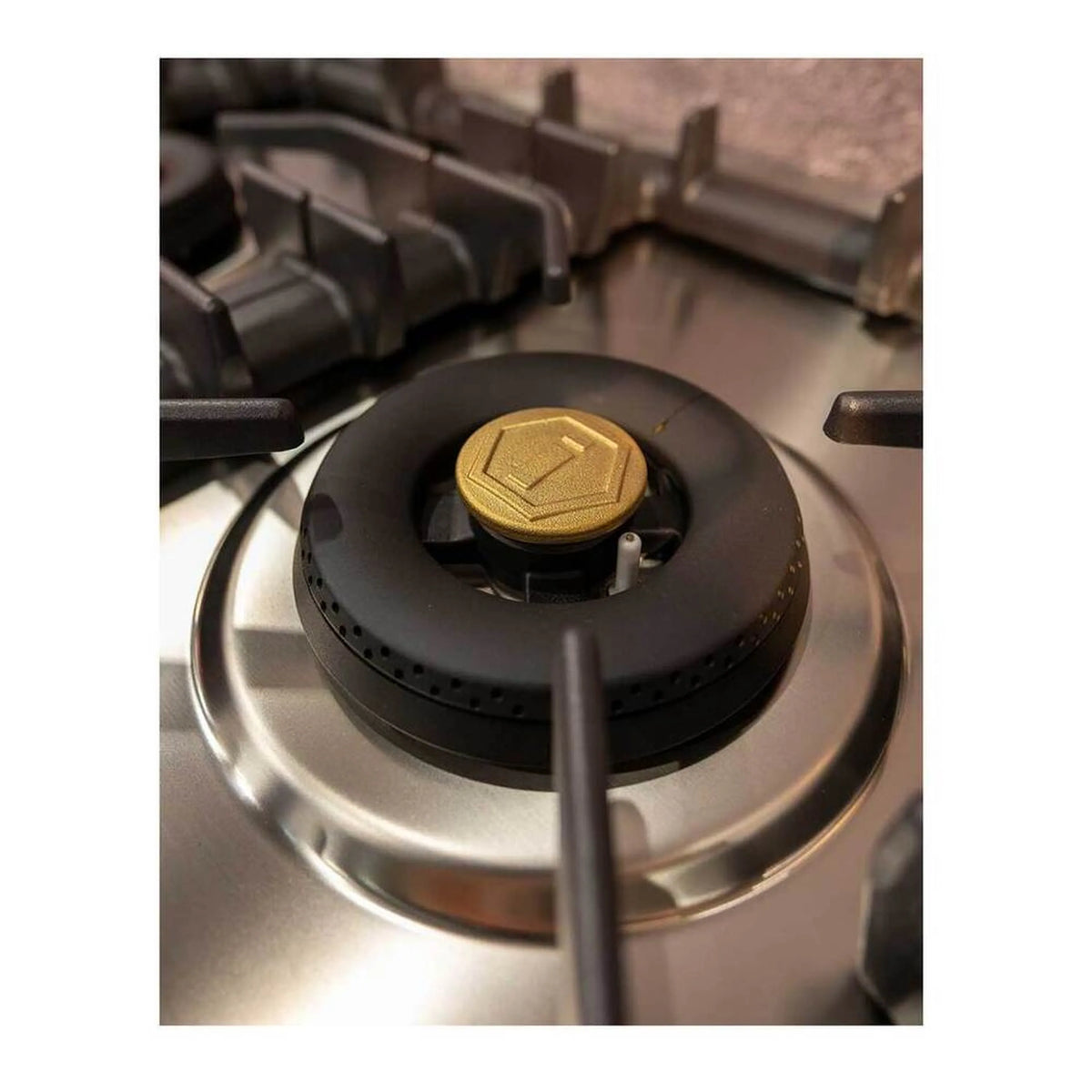 Stainless steel gas burner with black cap and gold center igniter cover