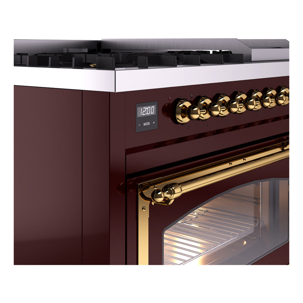 Burgundy dual fuel range close-up of brass control knobs and oven door with lit interior