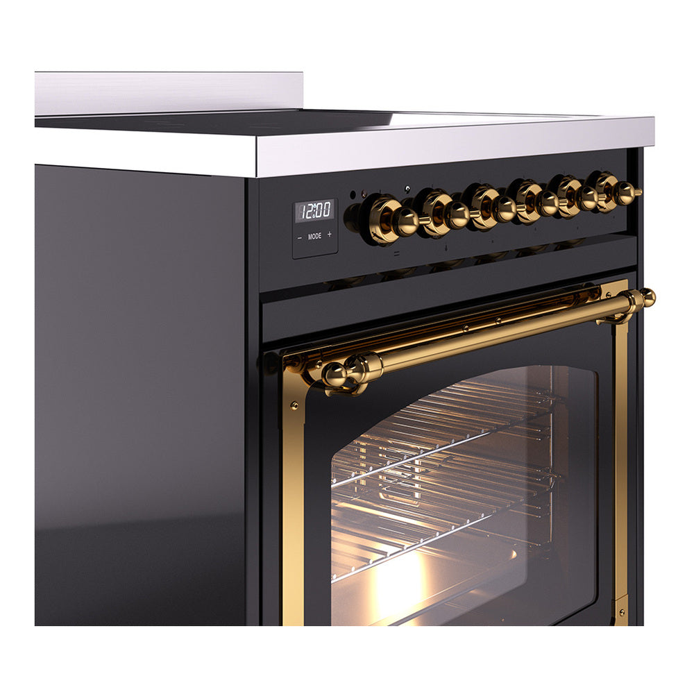 Close-up of black induction range controls and brass handle over glass door