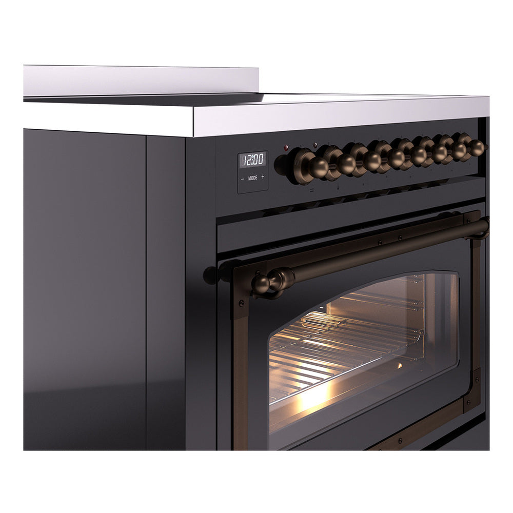 Glossy black induction range side detail with bronze control knobs and lit oven window.
