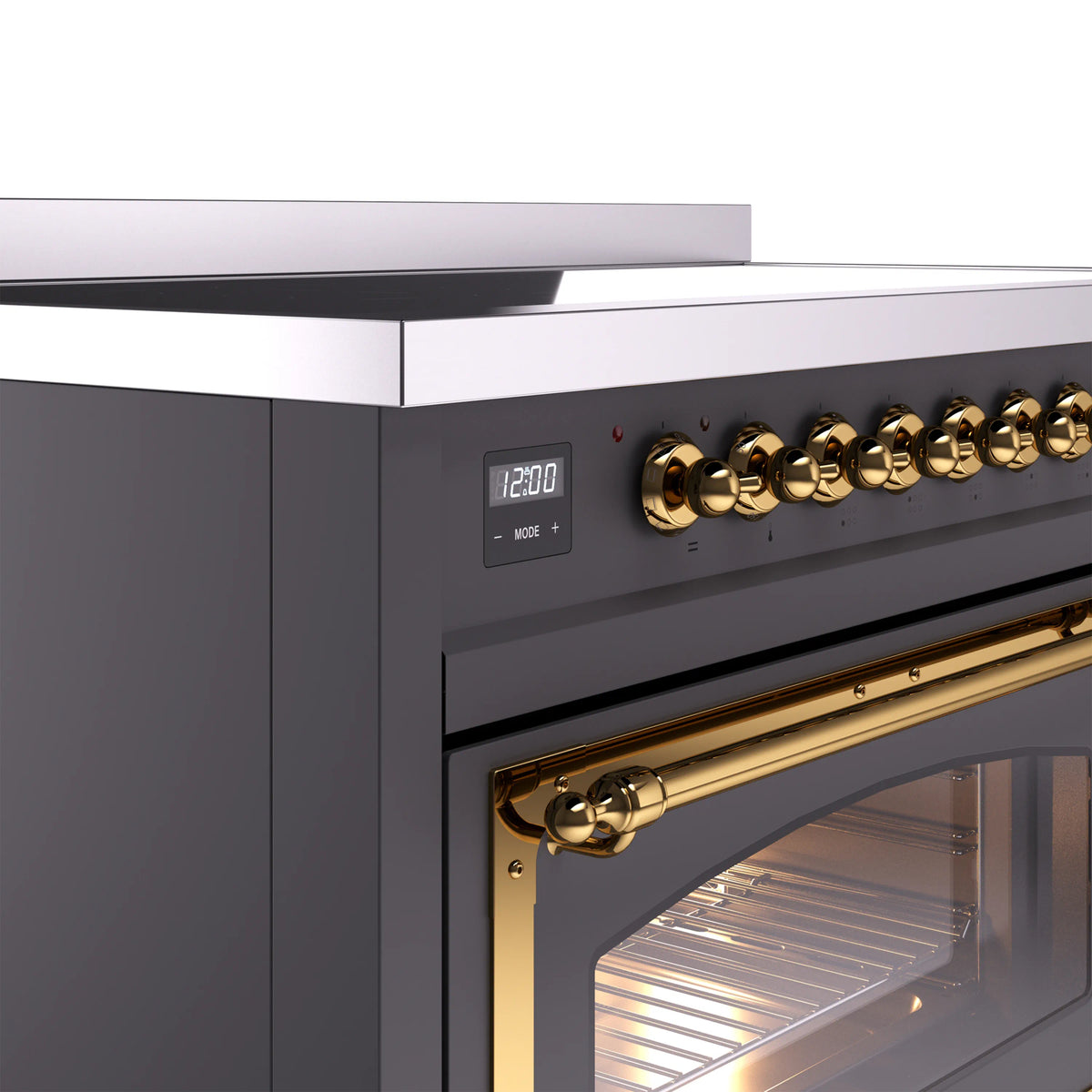 Matte graphite induction range control knobs with brass trim and glowing oven door window