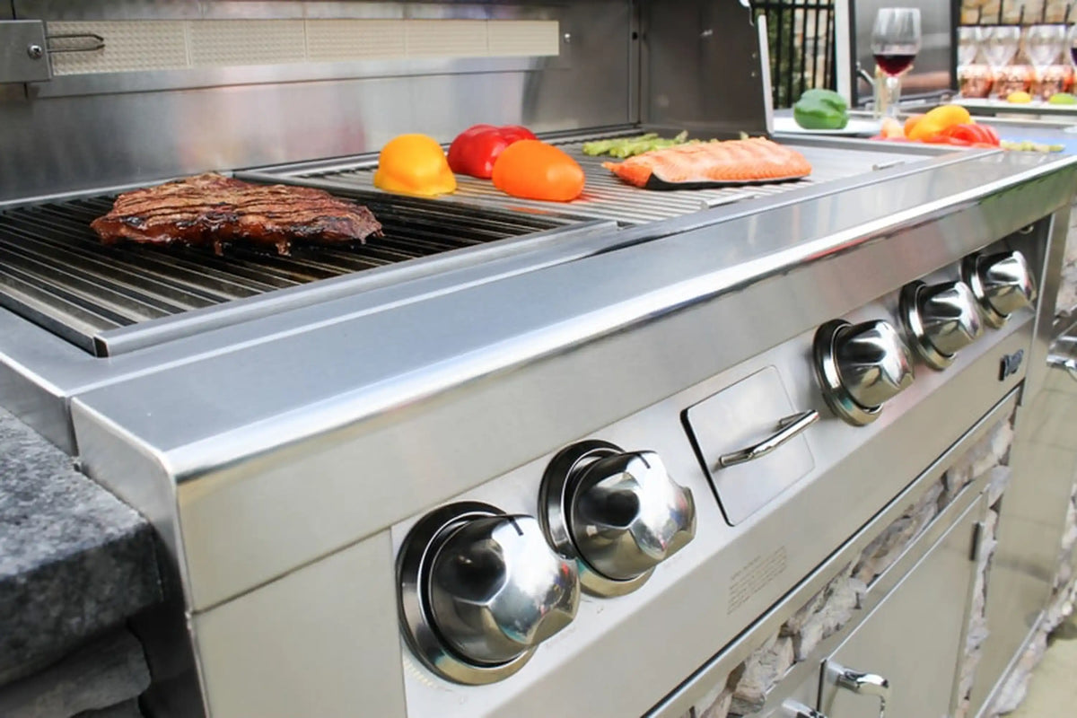 Stainless grill cooking surface with burgers and sliced vegetables on grates