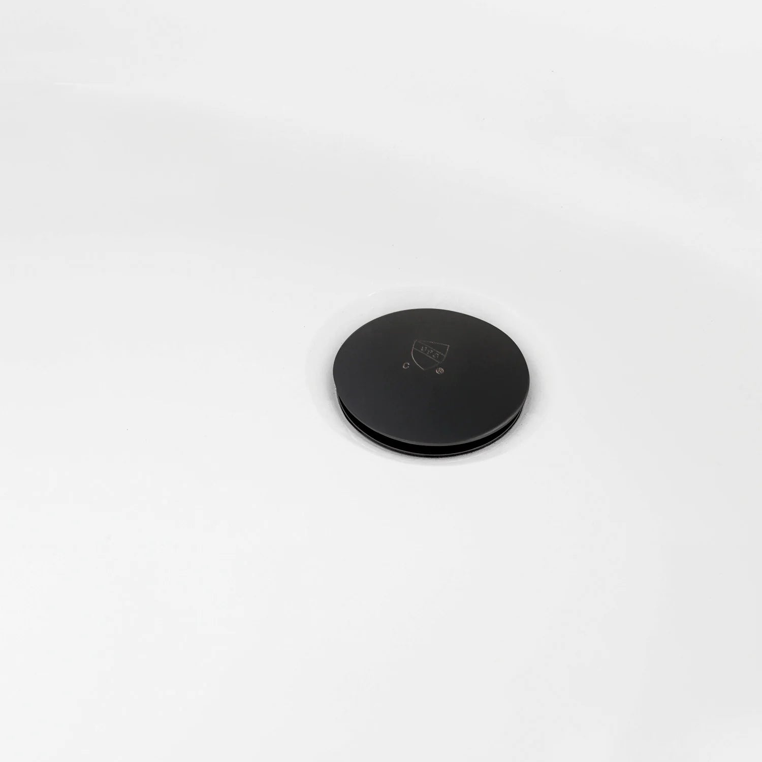 Matte black circular drain cover on white acrylic tub
