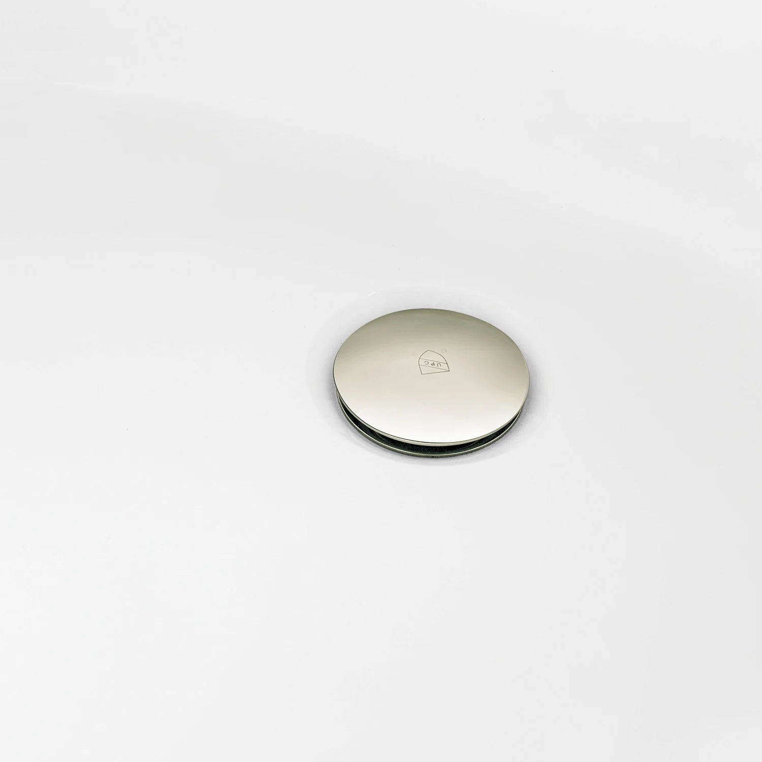 Polished nickel round tub drain cover on glossy white acrylic surface