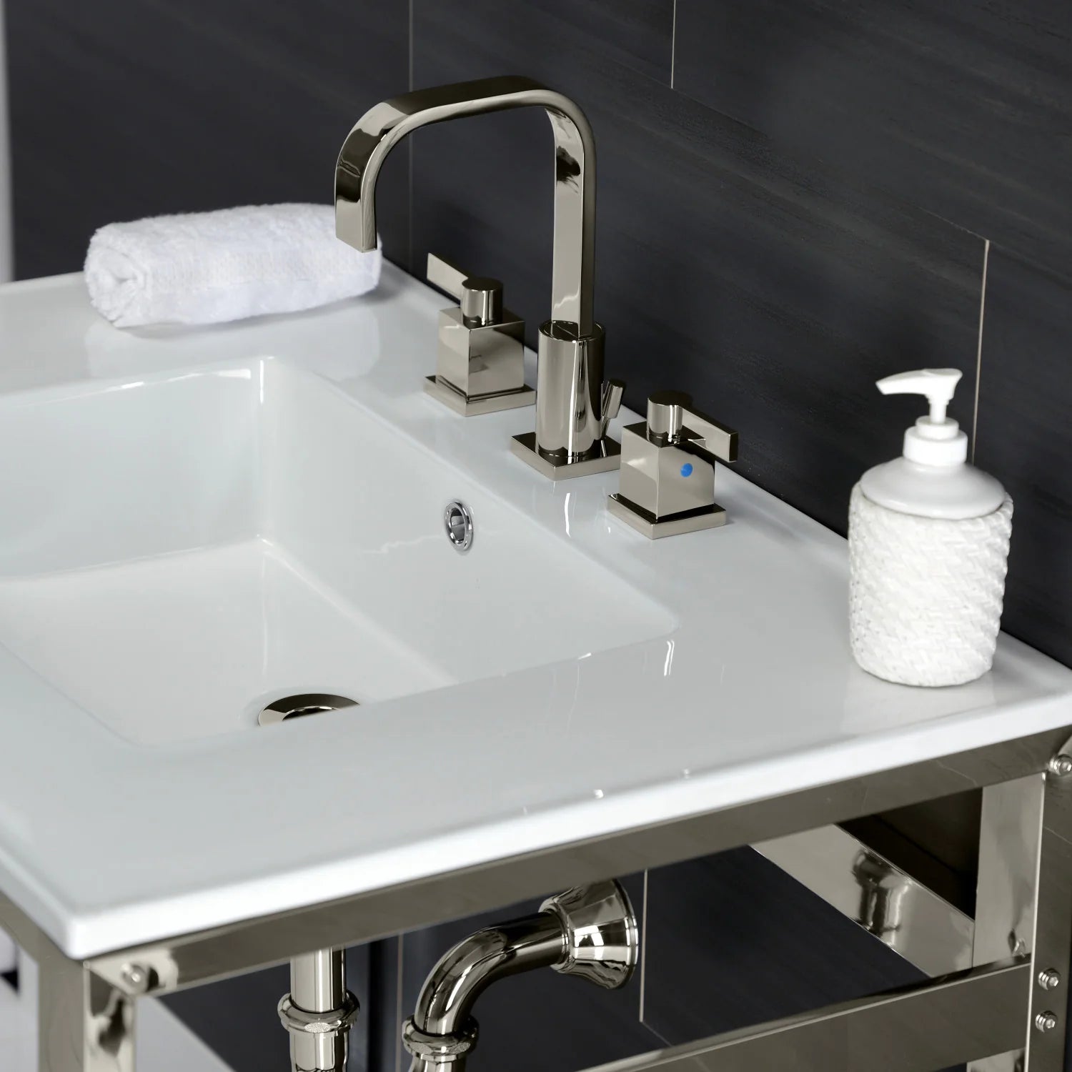 White sink basin with polished nickel faucet and soap dispenser on console frame