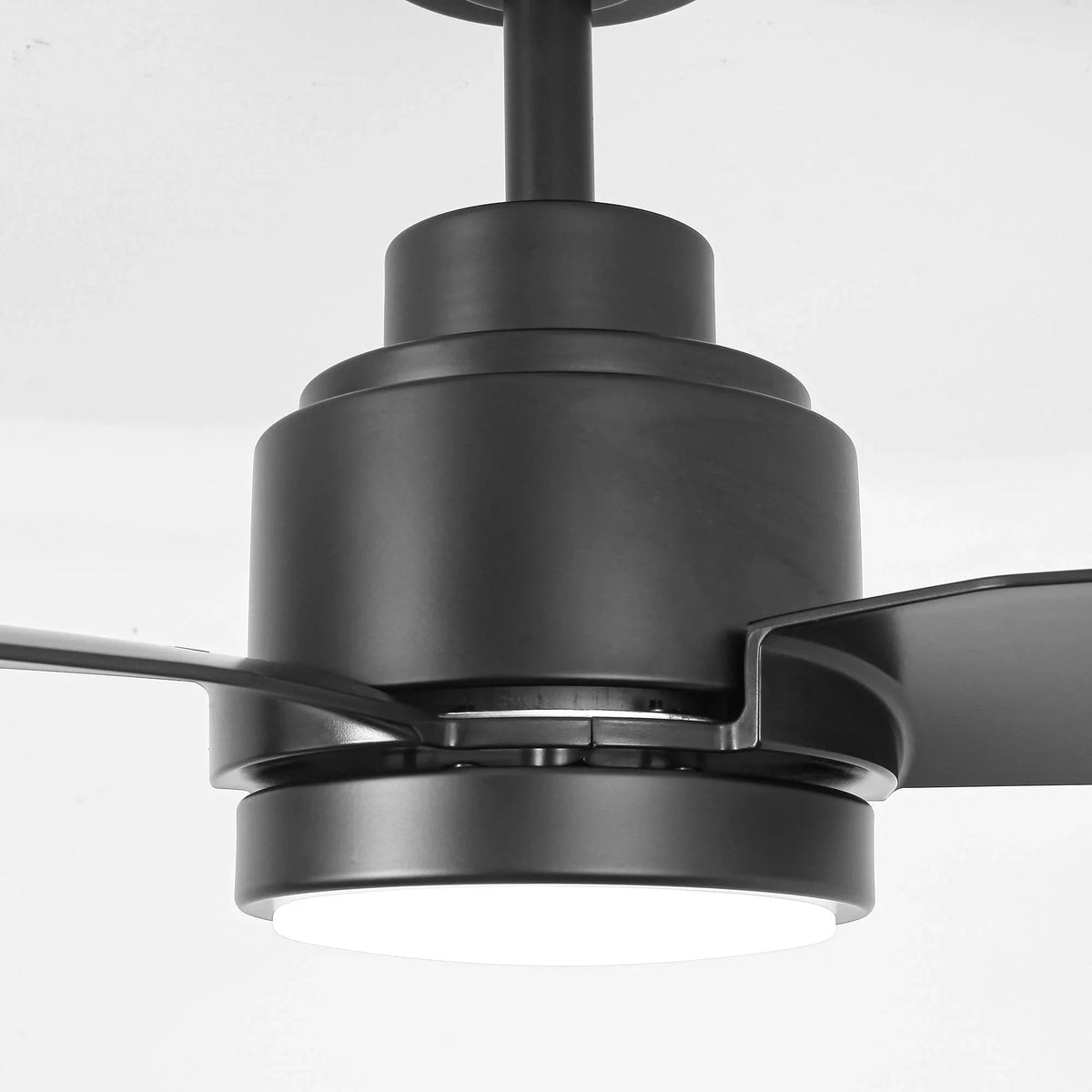 Close-up of black ceiling fan motor housing with LED light and three blades