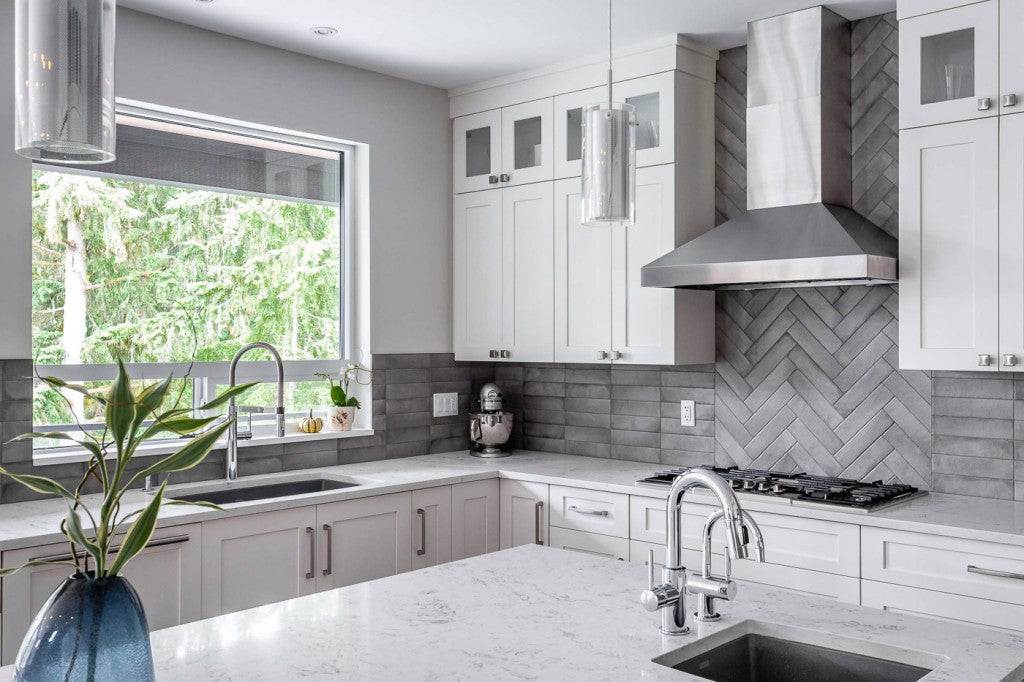 Stainless steel wall-mount range hood above a gas cooktop in a white kitchen