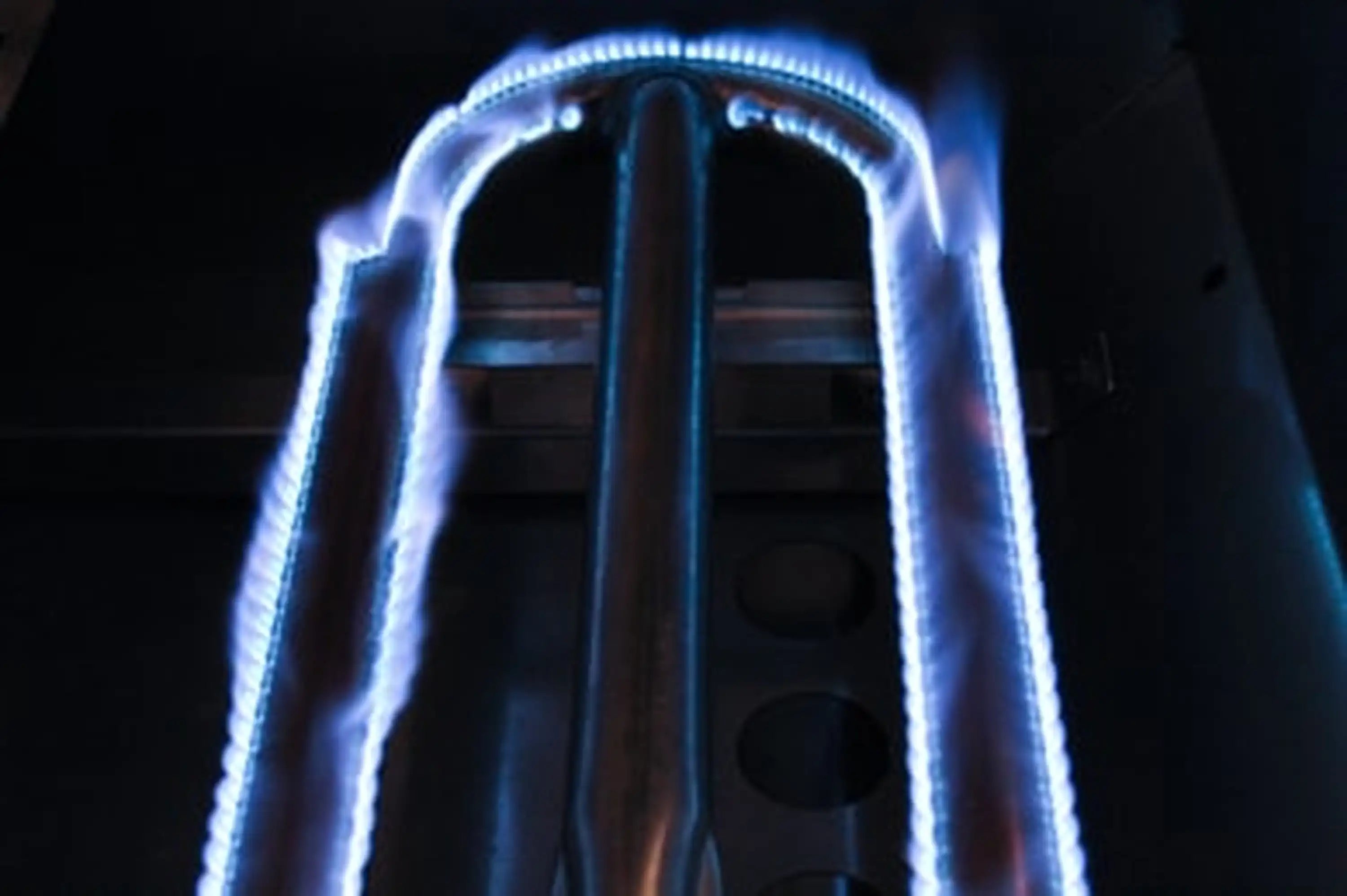 Stainless steel natural gas grill burners with visible blue flames