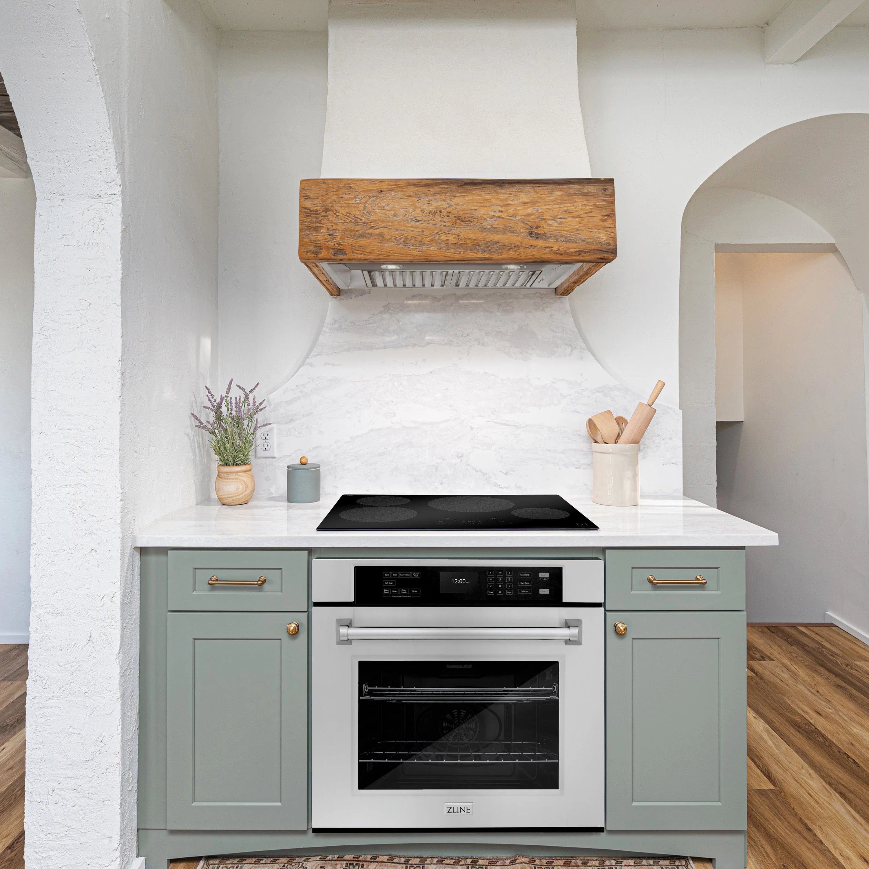 Stainless steel wall oven built into light mint cabinetry with range hood above
