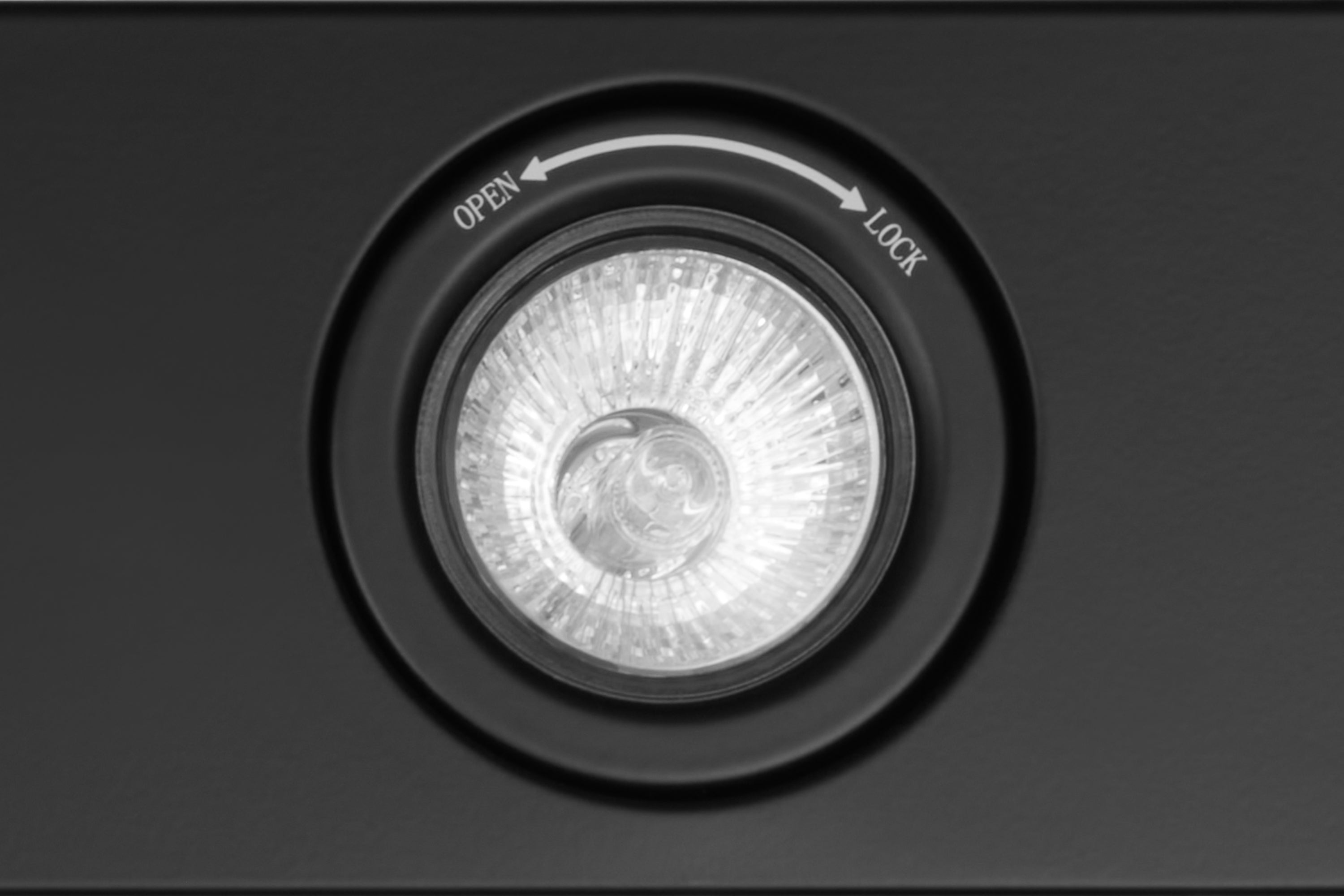 Matte black range hood fan opening with circular ring and open/lock markings.