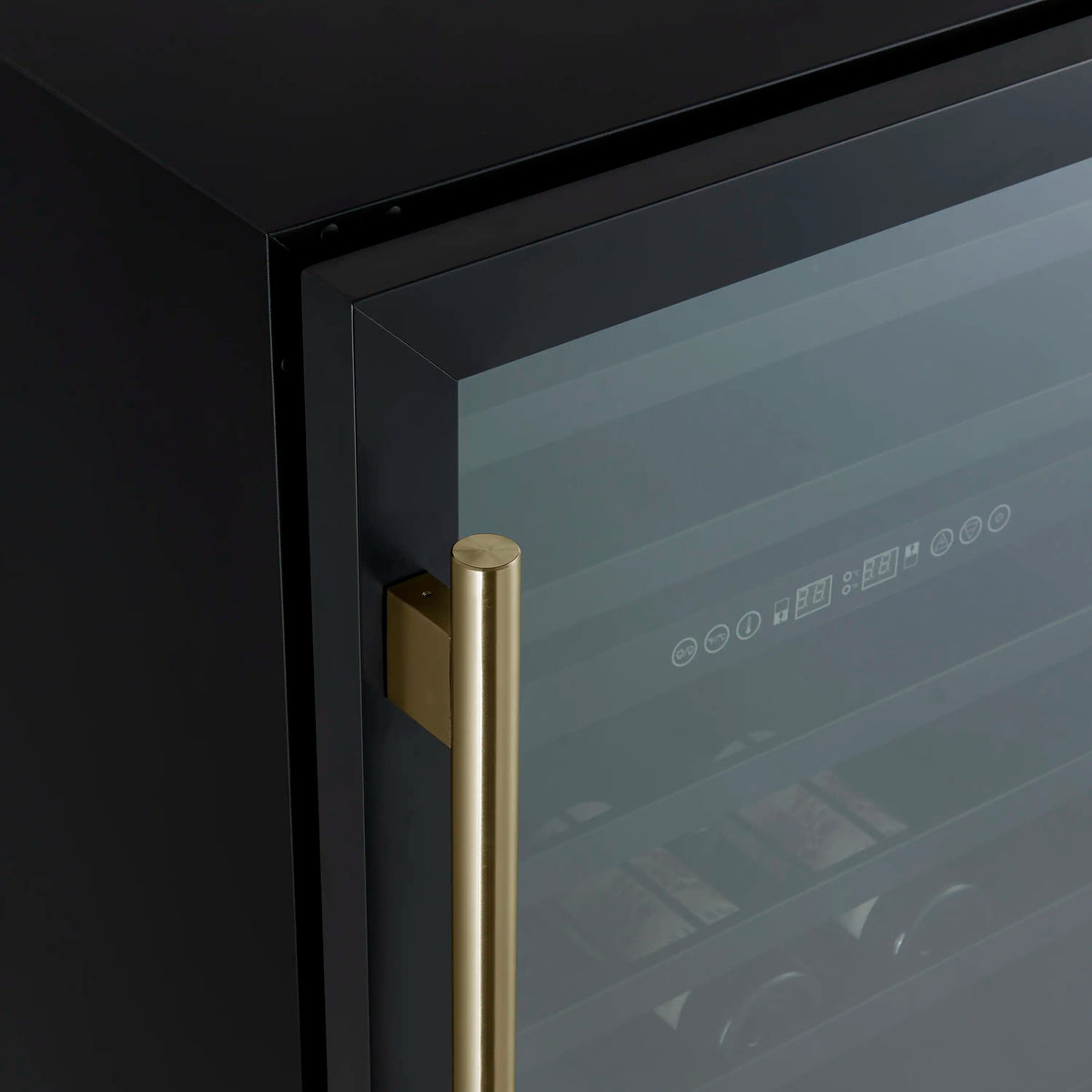 Detail of antique brass handle on black triple glass wine cooler door.