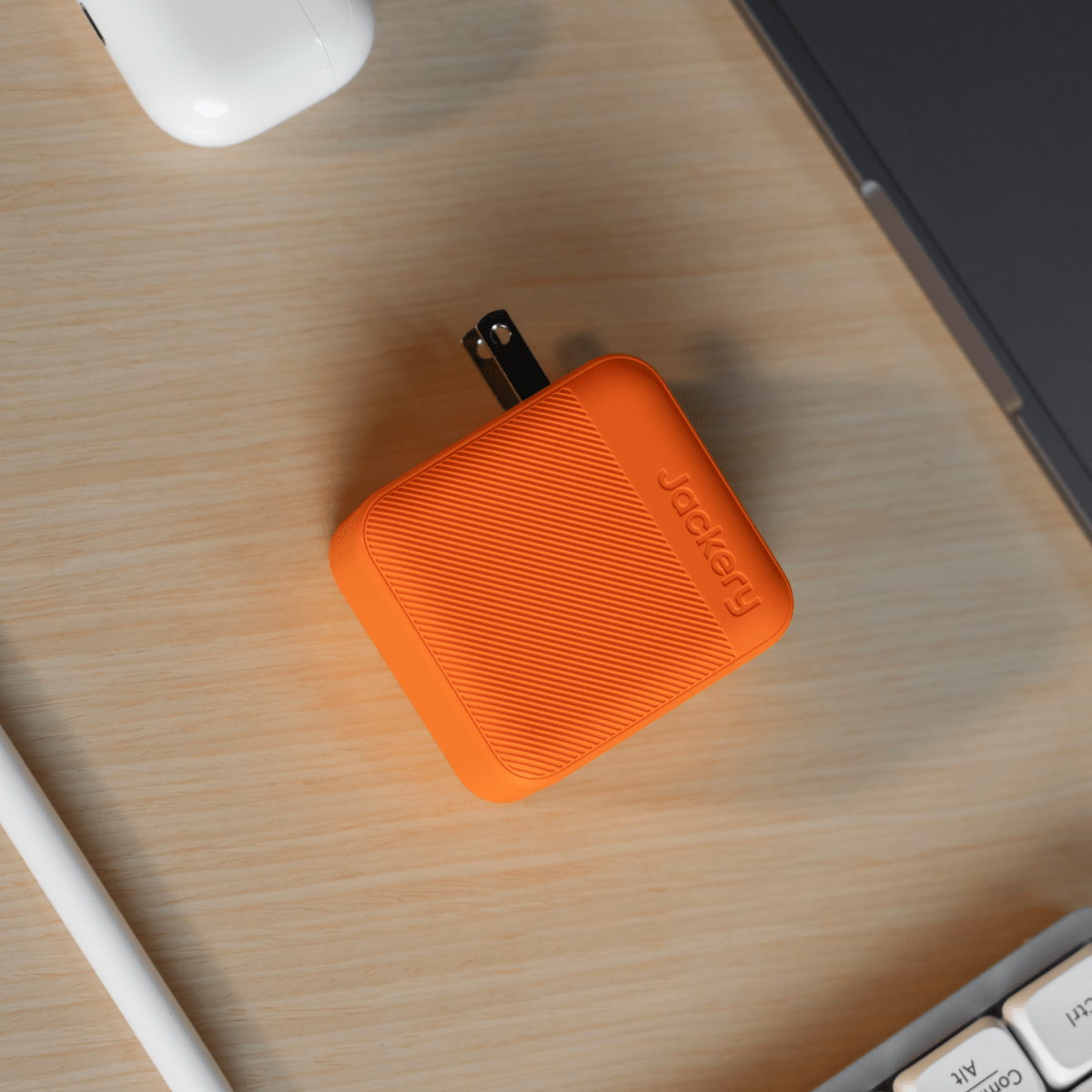 Orange Jackery charger cube on a wooden desk with ports facing upward