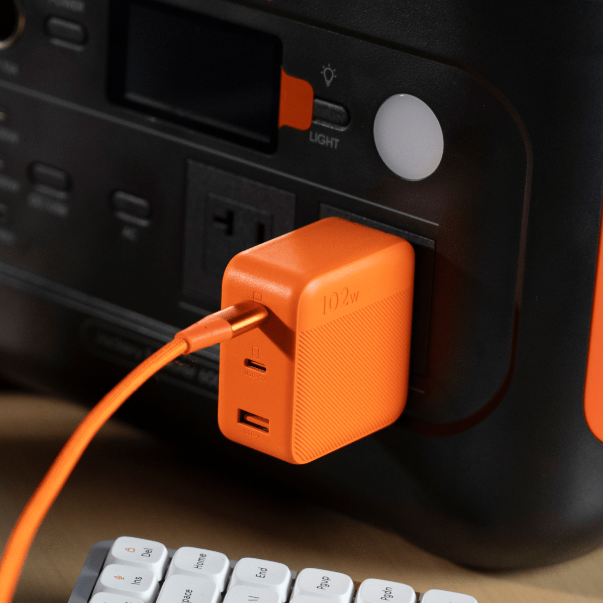 Orange Jackery charger plugged into a device panel, showing USB ports