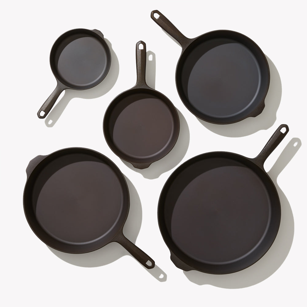 Set of five black cast iron frying pans with short loop handles